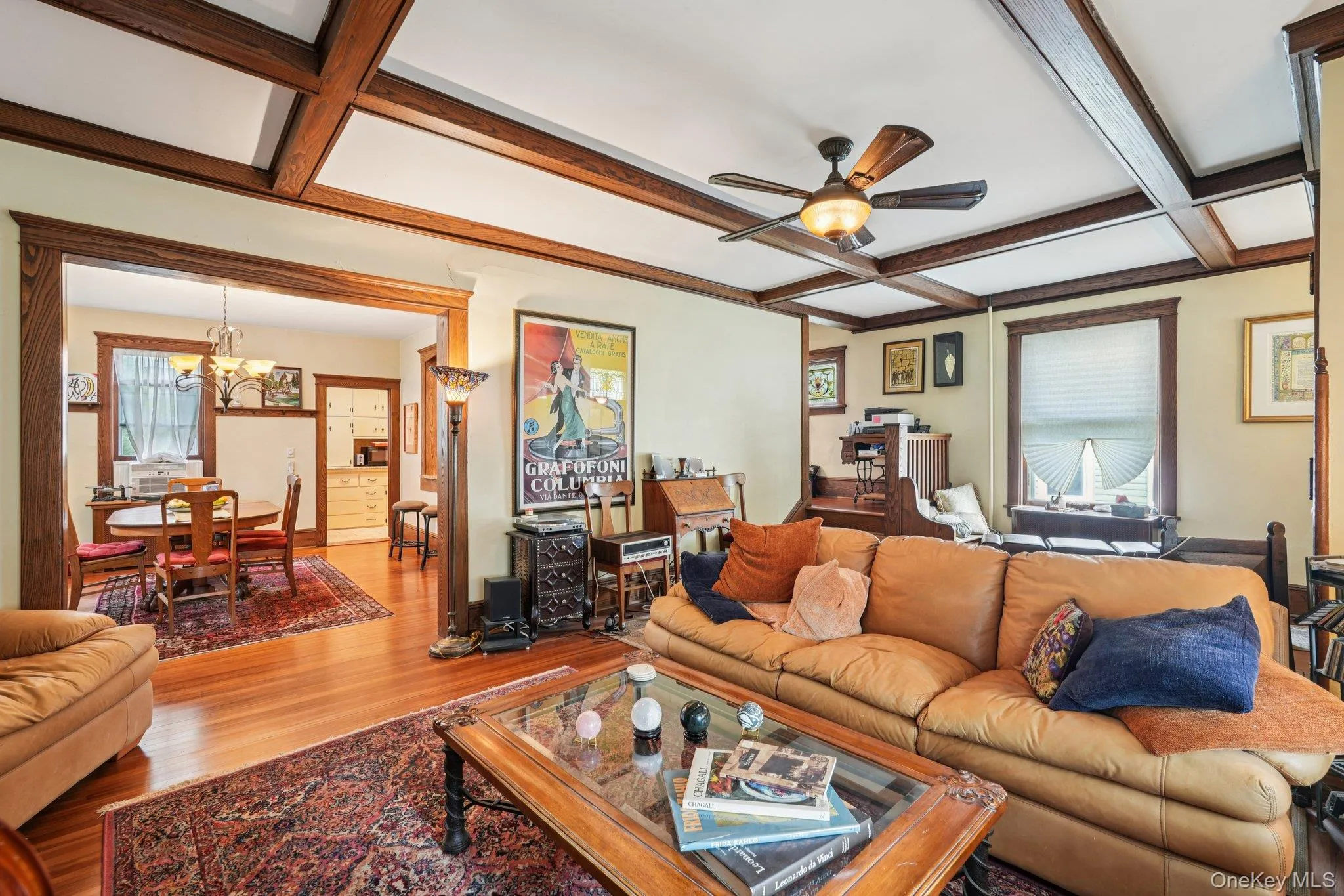 Living room with coffered ceiling, beam ceiling, wood finished floors, ceiling fan, and a chandelier Living room with coffered ceiling, beam ceiling, wood finished floors, ceiling fan, and a chandelier