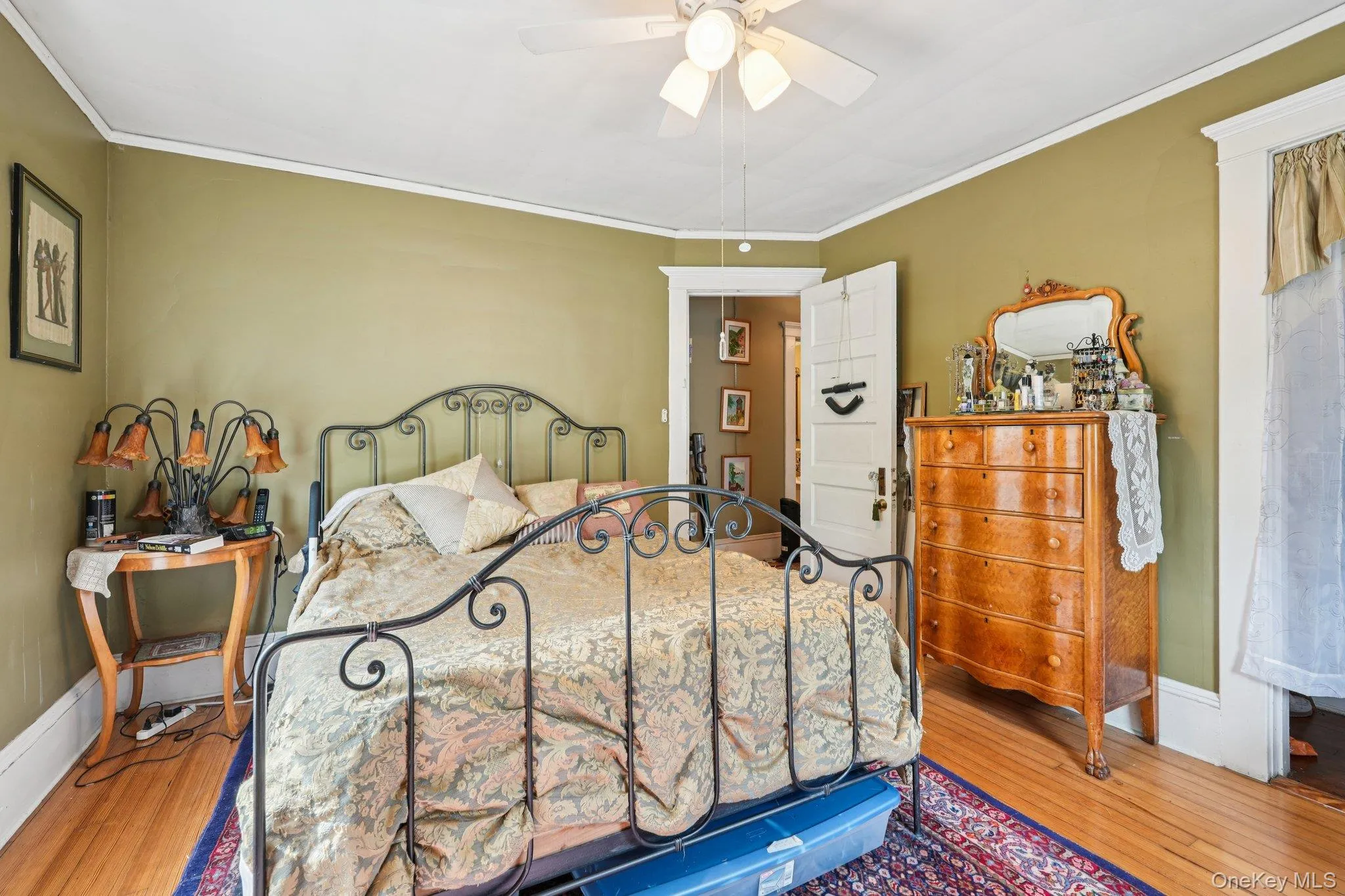 Bedroom with wood finished floors, ornamental molding, and a ceiling fan Bedroom with wood finished floors, ornamental molding, and a ceiling fan