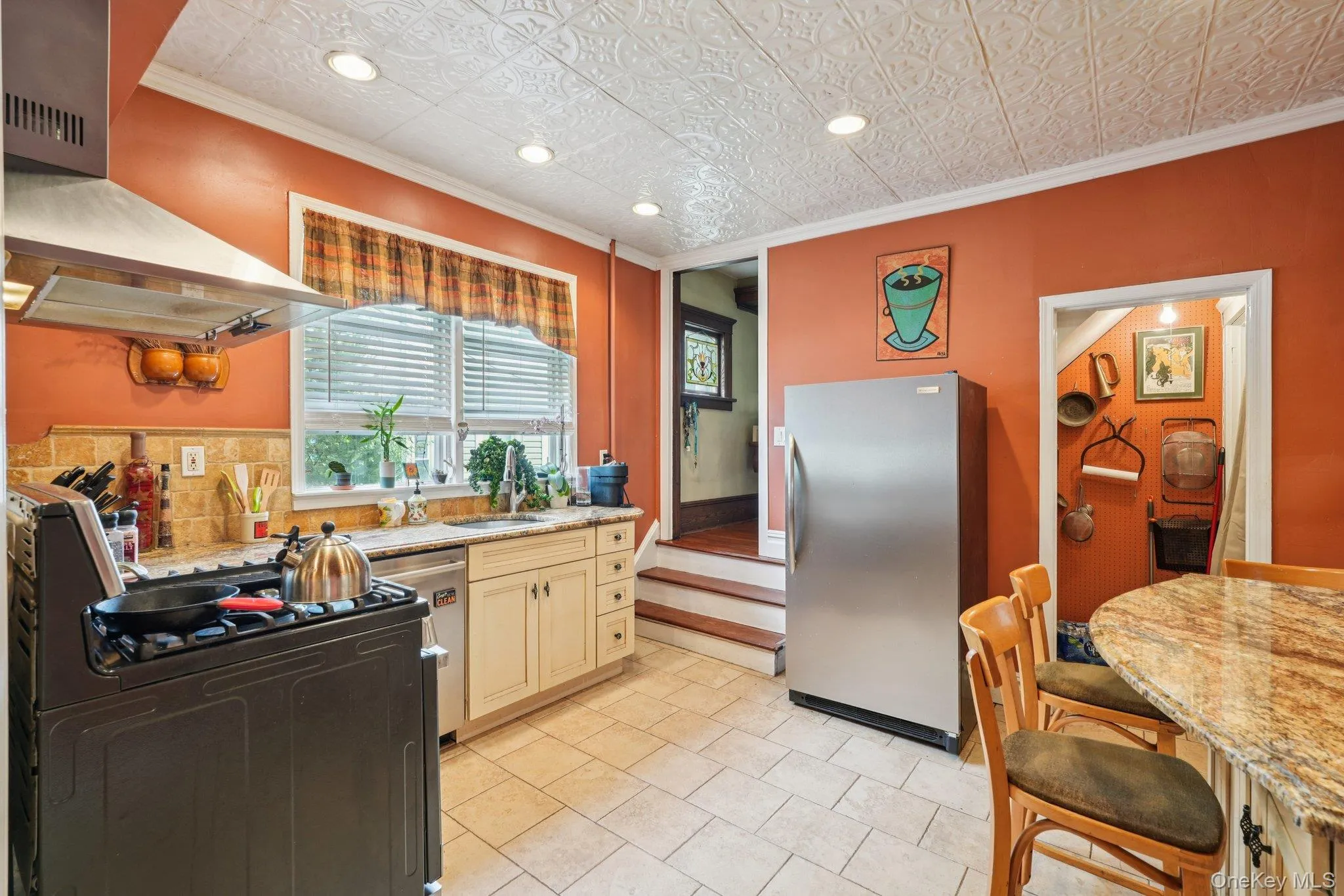 Kitchen with crown molding, stainless steel appliances, wall chimney exhaust hood, an ornate ceiling, and recessed lighting Kitchen with crown molding, stainless steel appliances, wall chimney exhaust hood, an ornate ceiling, and recessed lighting