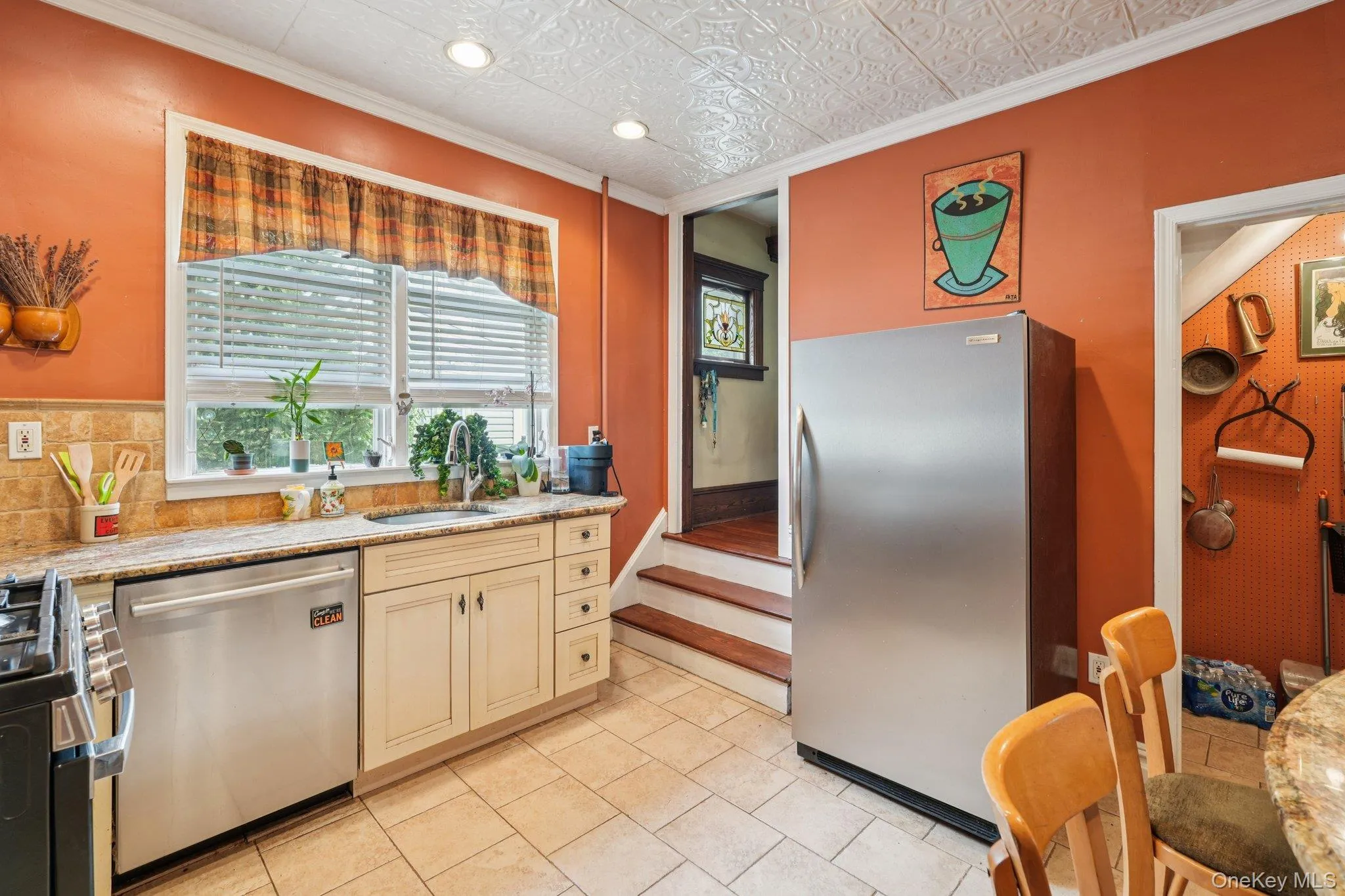 Kitchen featuring ornamental molding, appliances with stainless steel finishes, light stone countertops, an ornate ceiling, and cream cabinets Kitchen featuring ornamental molding, appliances with stainless steel finishes, light stone countertops, an ornate ceiling, and cream cabinets