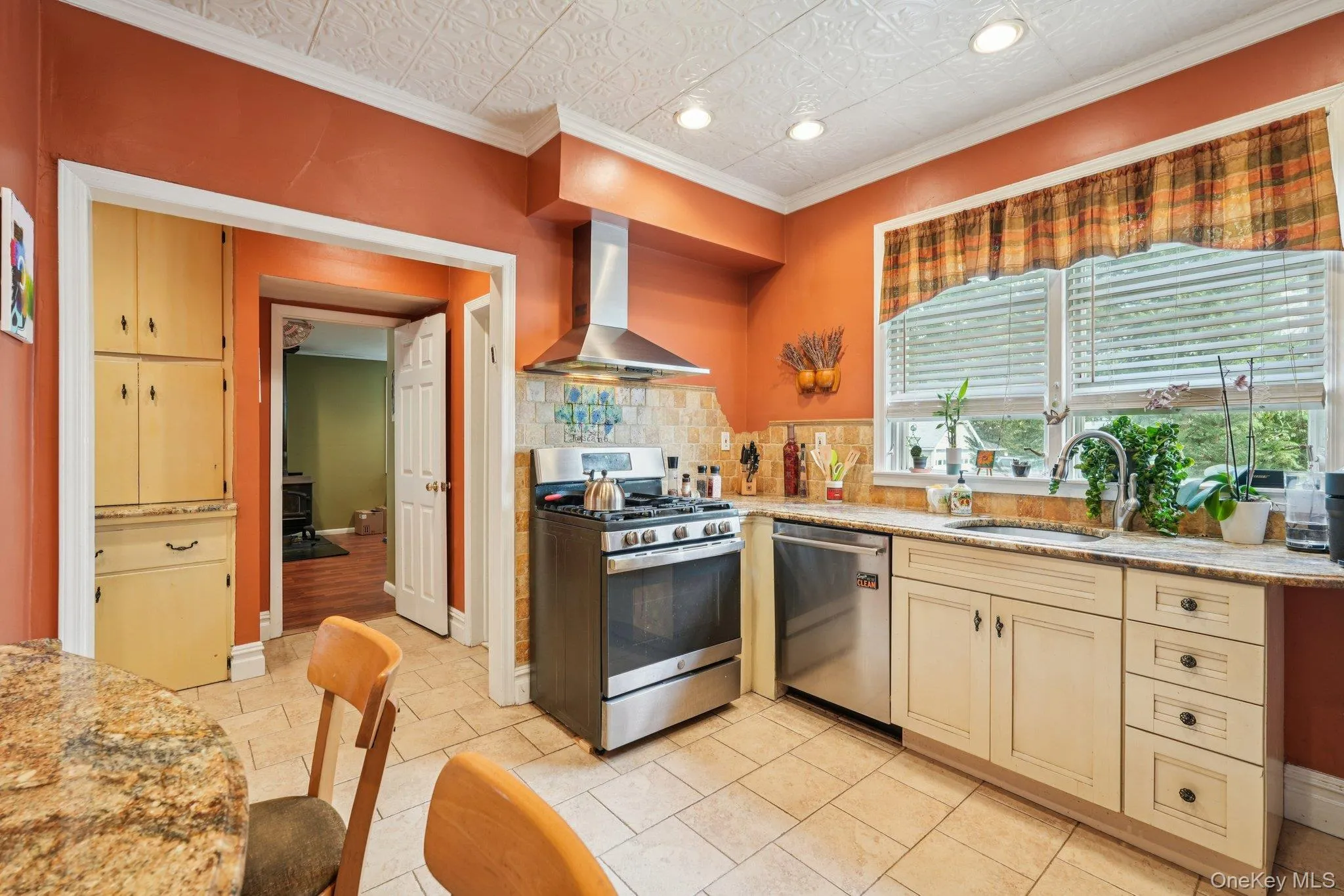 Kitchen featuring appliances with stainless steel finishes, extractor fan, light stone countertops, crown molding, and an ornate ceiling Kitchen featuring appliances with stainless steel finishes, extractor fan, light stone countertops, crown molding, and an ornate ceiling