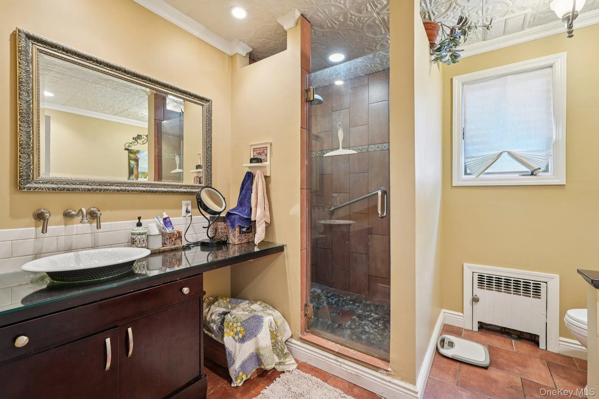 Bathroom with ornamental molding, a shower stall, radiator heating unit, vanity, and tile patterned flooring Bathroom with ornamental molding, a shower stall, radiator heating unit, vanity, and tile patterned flooring
