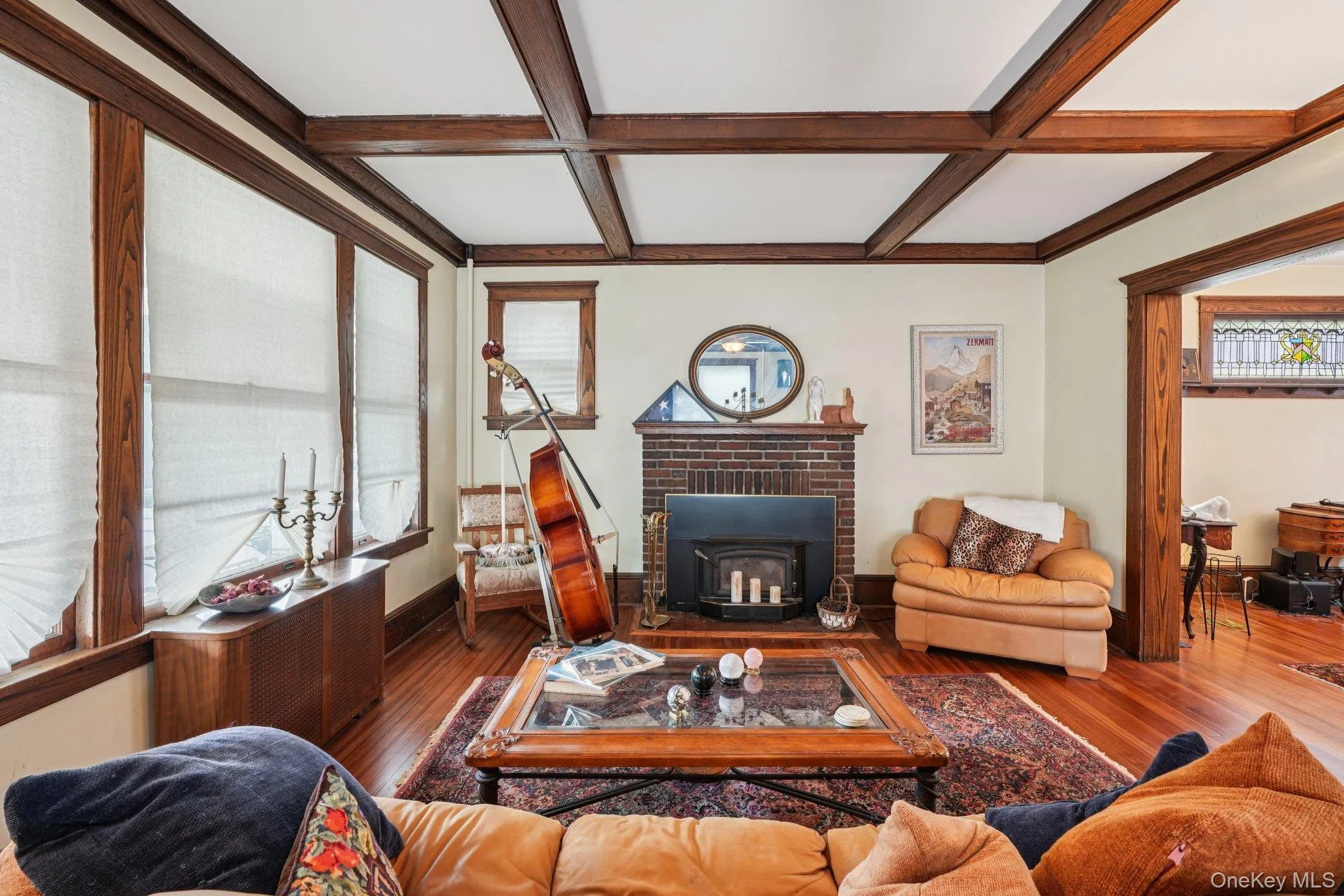 Living room featuring coffered ceiling, beamed ceiling, wood finished floors, and a wood stove Living room featuring coffered ceiling, beamed ceiling, wood finished floors, and a wood stove