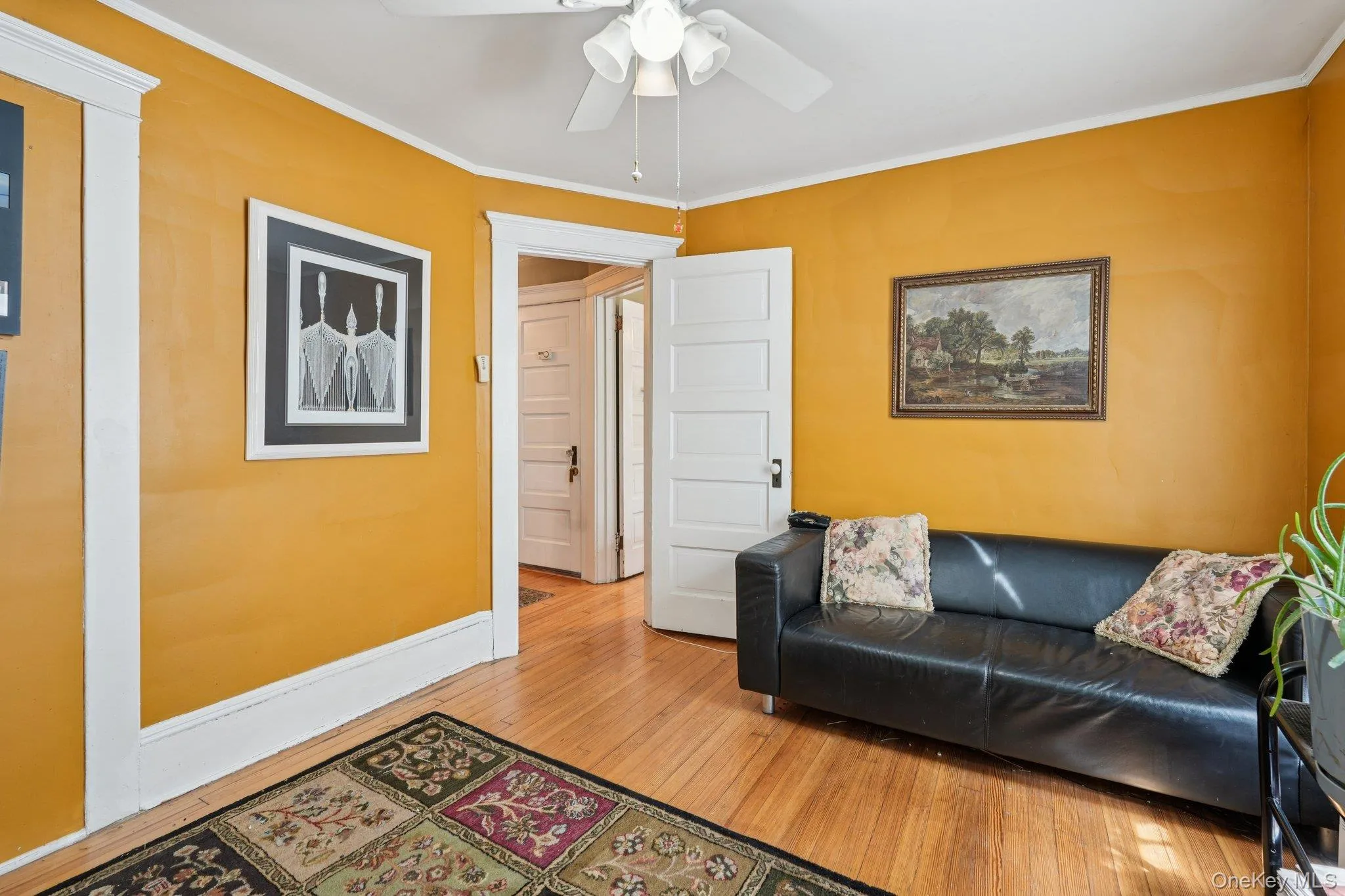 Living room featuring crown molding, hardwood / wood-style flooring, and a ceiling fan Living room featuring crown molding, hardwood / wood-style flooring, and a ceiling fan