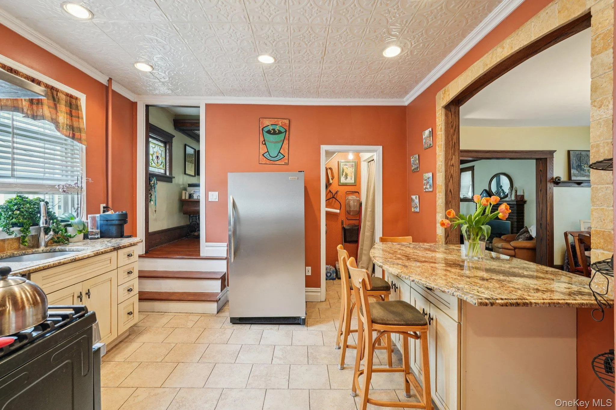 Kitchen with crown molding, freestanding refrigerator, recessed lighting, light stone counters, and a kitchen breakfast bar Kitchen with crown molding, freestanding refrigerator, recessed lighting, light stone counters, and a kitchen breakfast bar