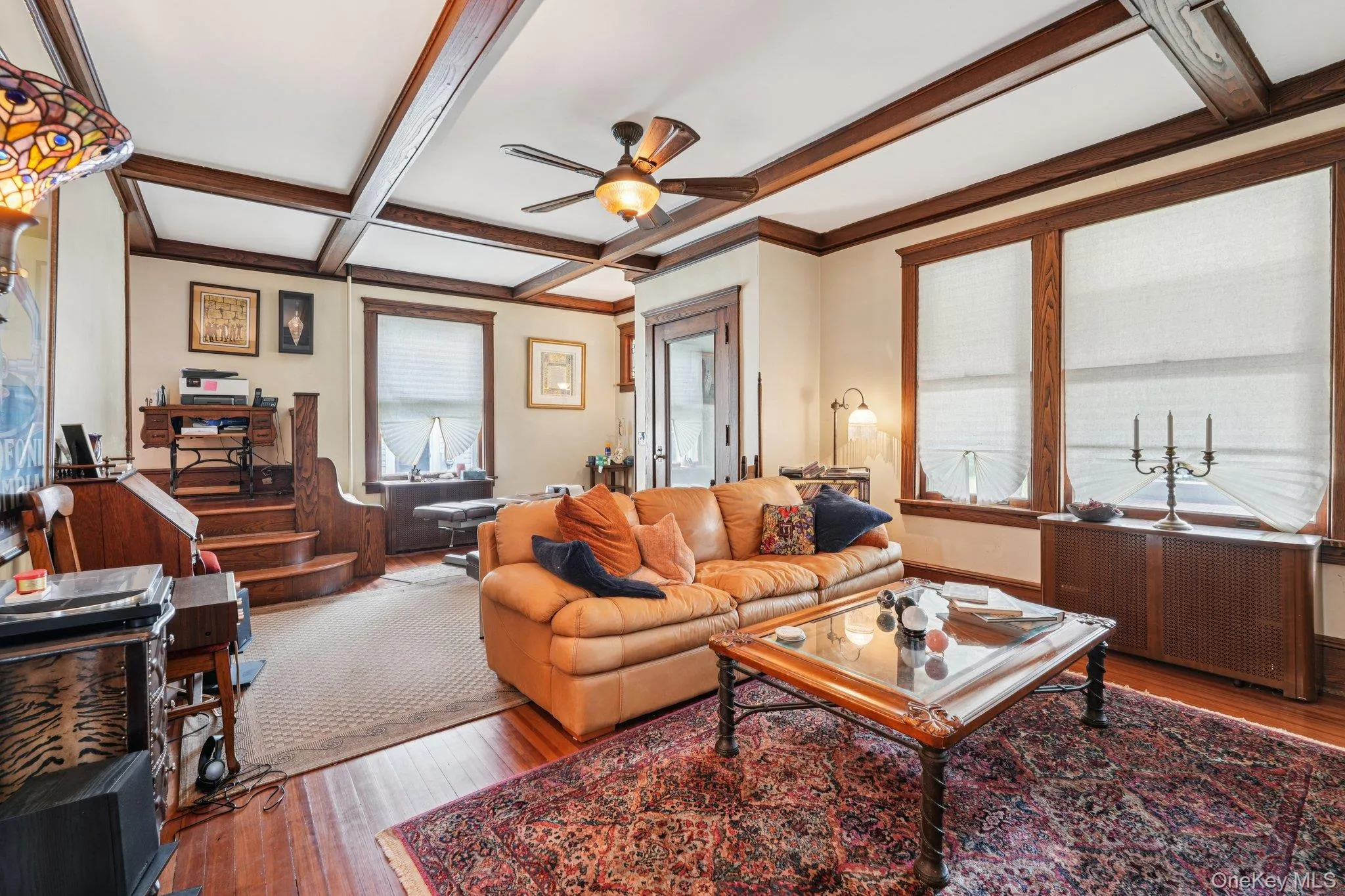 Living room with coffered ceiling, hardwood / wood-style flooring, beam ceiling, and ceiling fan Living room with coffered ceiling, hardwood / wood-style flooring, beam ceiling, and ceiling fan