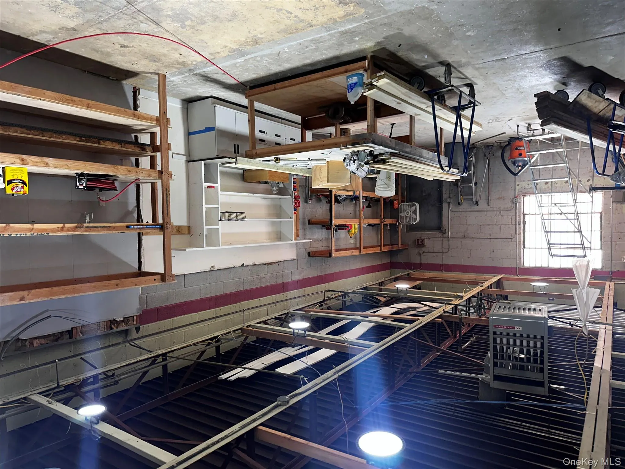 Basement with concrete block wall, a heating unit, and a workshop area Basement with concrete block wall, a heating unit, and a workshop area