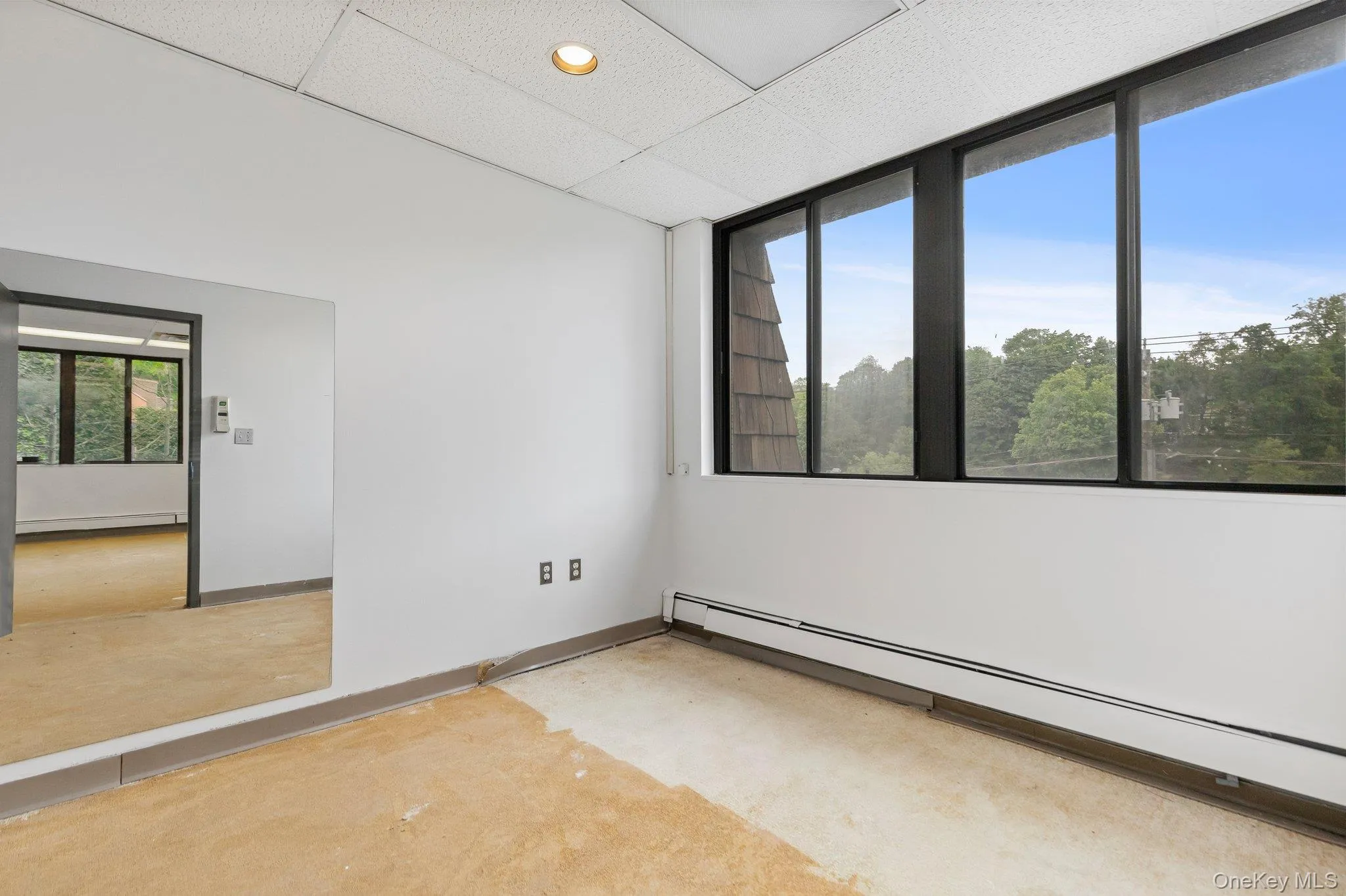 Unfurnished room featuring baseboard heating, a drop ceiling, concrete flooring, and recessed lighting Unfurnished room featuring baseboard heating, a drop ceiling, concrete flooring, and recessed lighting
