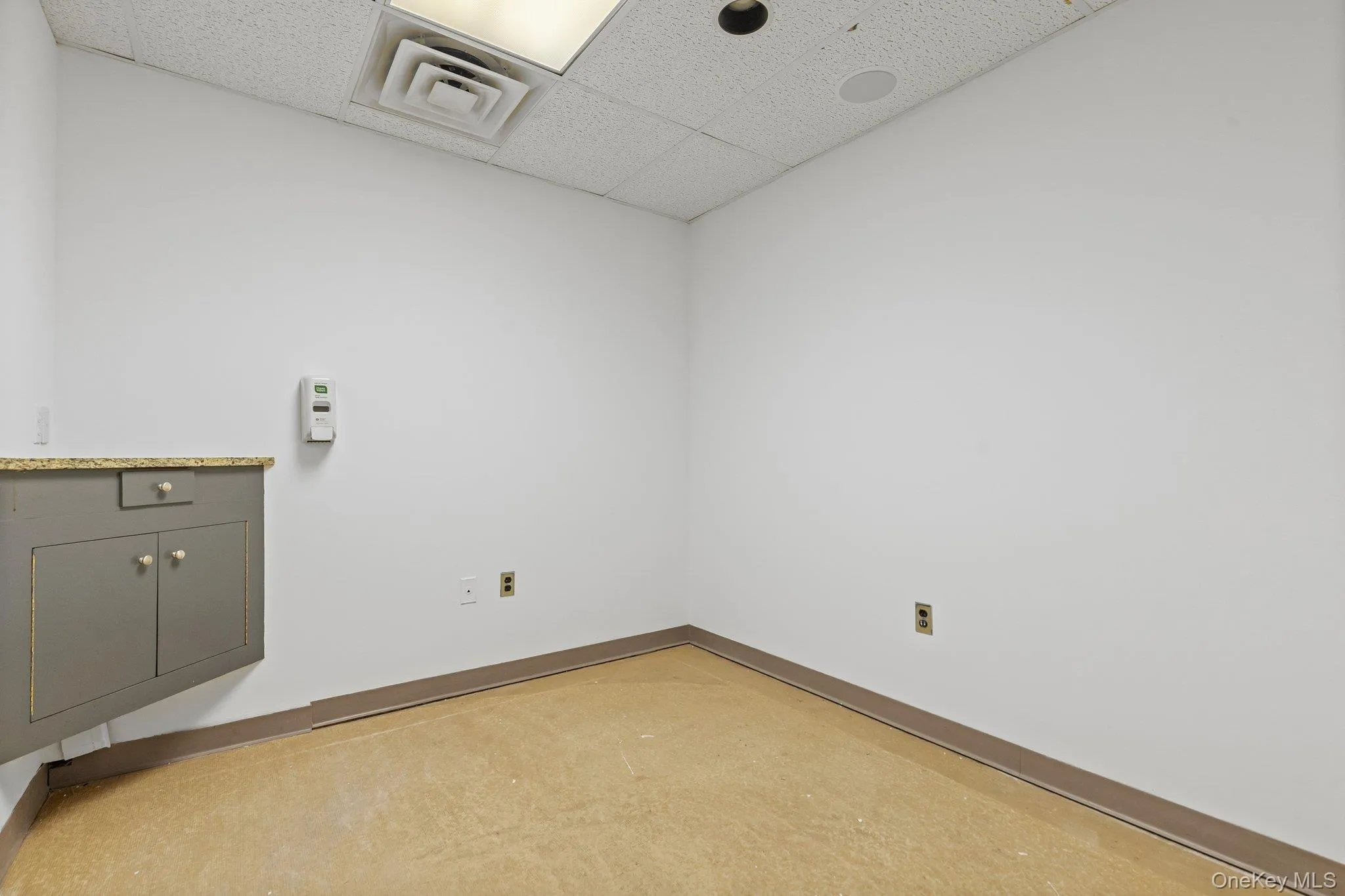 Empty room with a drop ceiling and baseboards Empty room with a drop ceiling and baseboards