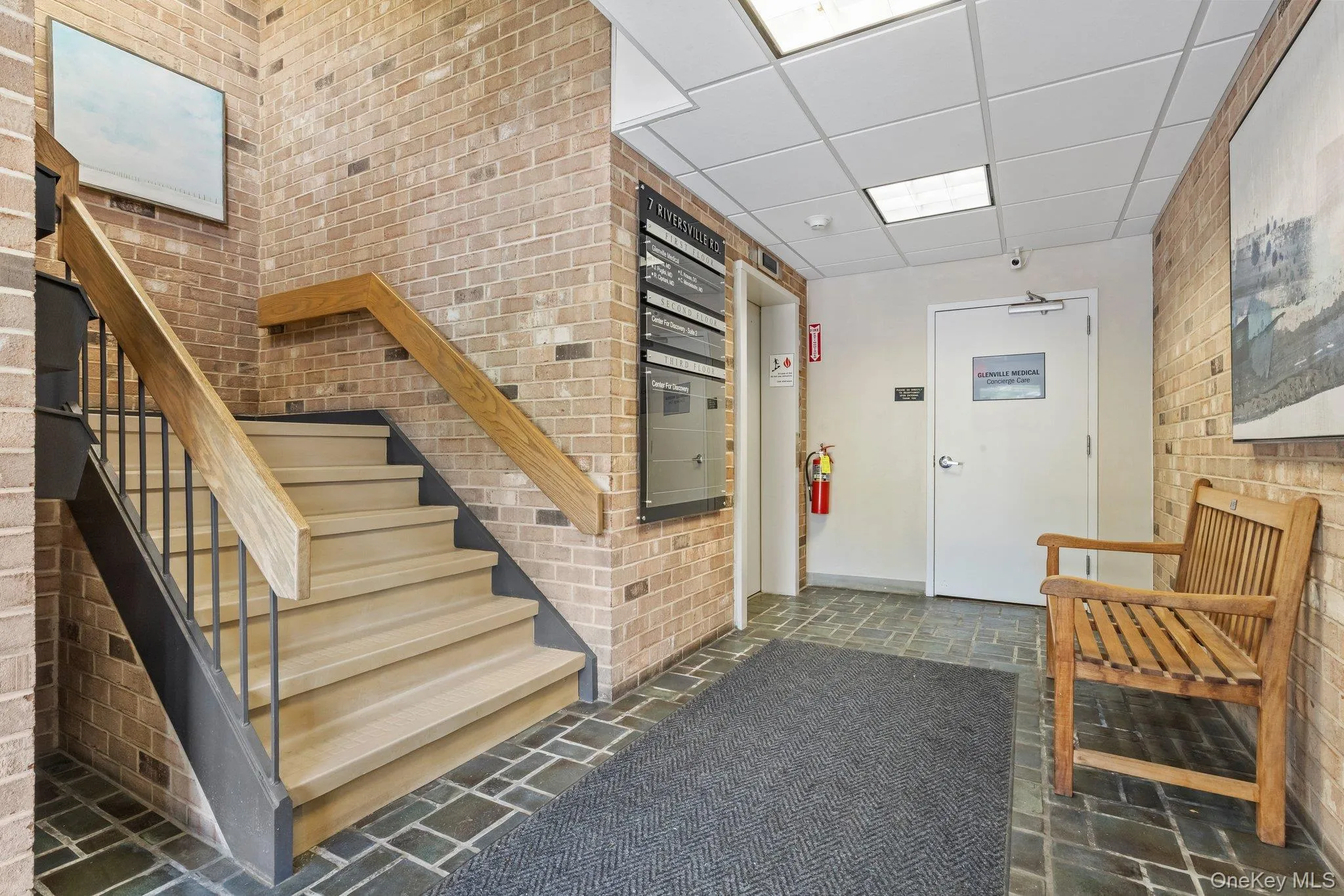 Stairway featuring brick wall, a paneled ceiling, and stone finish floors Stairway featuring brick wall, a paneled ceiling, and stone finish floors