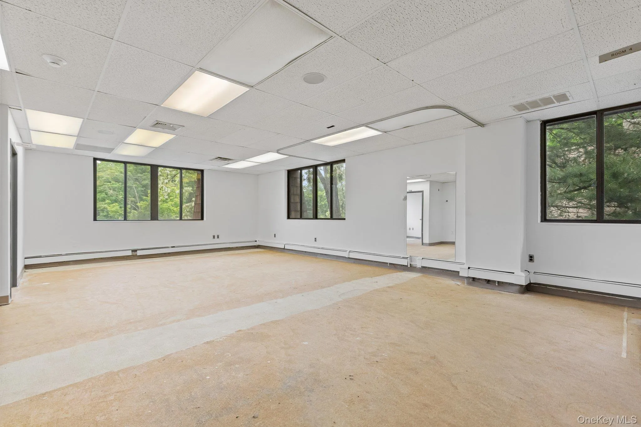 Spare room featuring a drop ceiling, baseboard heating, and concrete floors Spare room featuring a drop ceiling, baseboard heating, and concrete floors