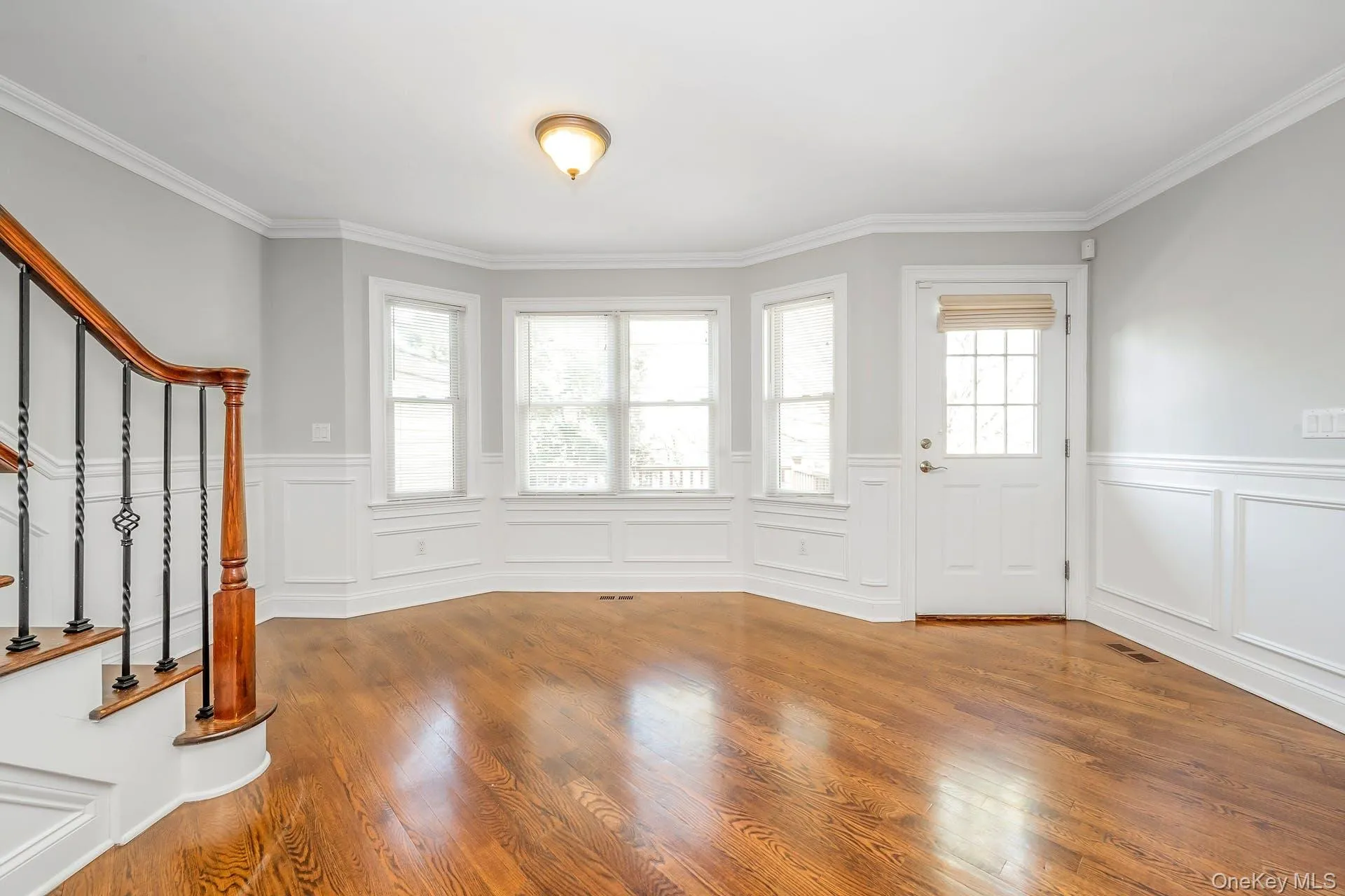 Foyer featuring plenty of natural light, stairs, wood finished floors, a decorative wall, and ornamental molding Foyer featuring plenty of natural light, stairs, wood finished floors, a decorative wall, and ornamental molding