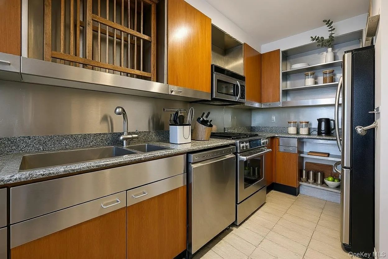 Kitchen featuring brown cabinets, dark stone counters, appliances with stainless steel finishes, light tile patterned flooring, and modern cabinets Kitchen featuring brown cabinets, dark stone counters, appliances with stainless steel finishes, light tile patterned flooring, and modern cabinets