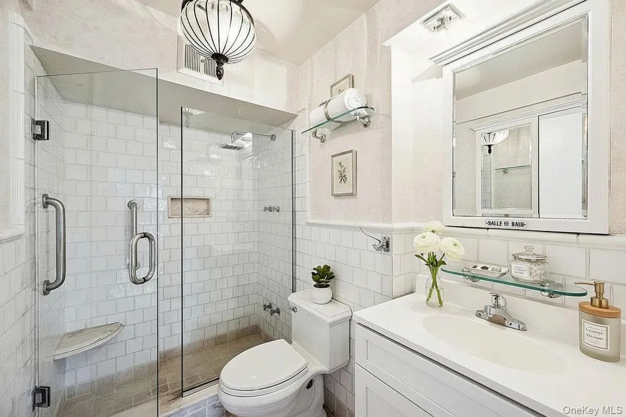 Bathroom featuring tile walls, vanity, and a shower stall Bathroom featuring tile walls, vanity, and a shower stall