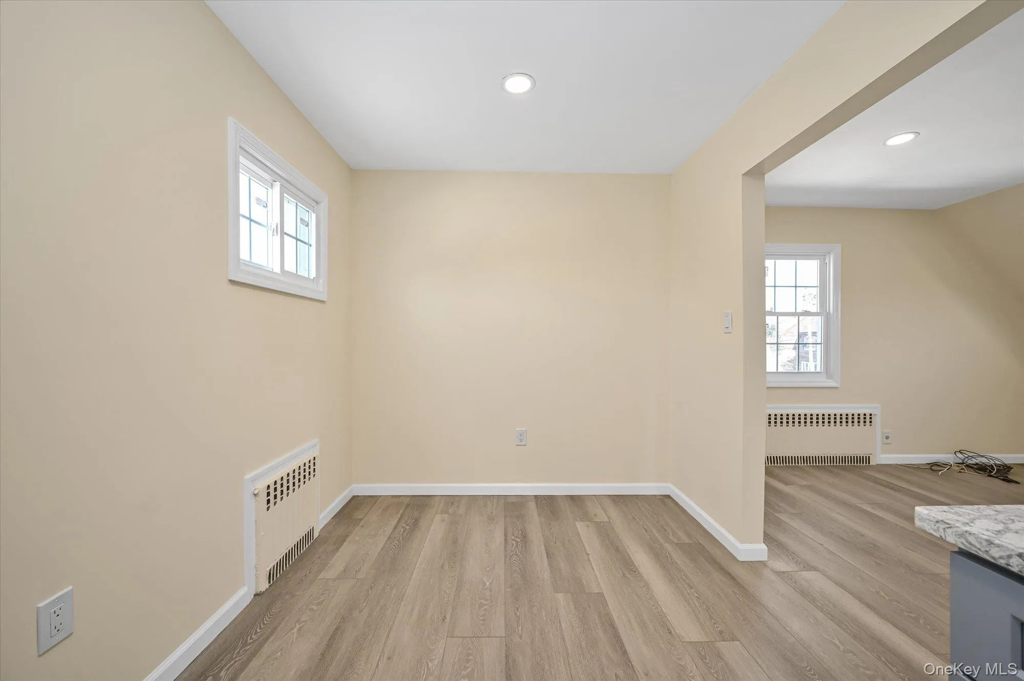 Unfurnished dining area featuring plenty of natural light, light wood-type flooring, radiator heating unit, and recessed lighting Unfurnished dining area featuring plenty of natural light, light wood-type flooring, radiator heating unit, and recessed lighting