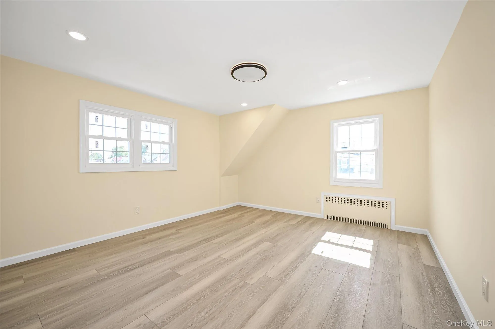 Additional living space with radiator heating unit, plenty of natural light, light wood finished floors, and recessed lighting Additional living space with radiator heating unit, plenty of natural light, light wood finished floors, and recessed lighting