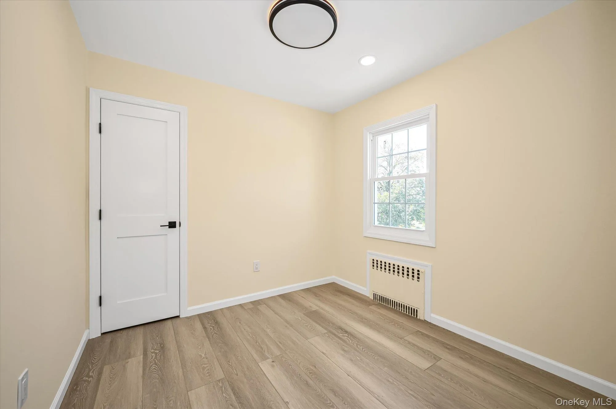 Unfurnished room with radiator, light wood-type flooring, and recessed lighting Unfurnished room with radiator, light wood-type flooring, and recessed lighting
