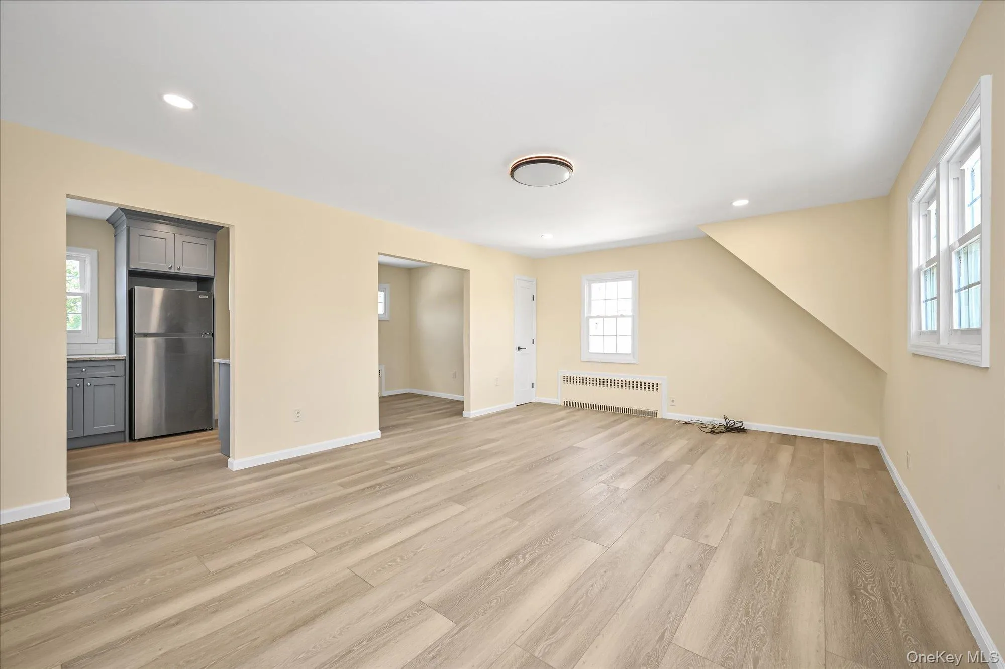 Unfurnished living room featuring recessed lighting, light wood-type flooring, and radiator Unfurnished living room featuring recessed lighting, light wood-type flooring, and radiator