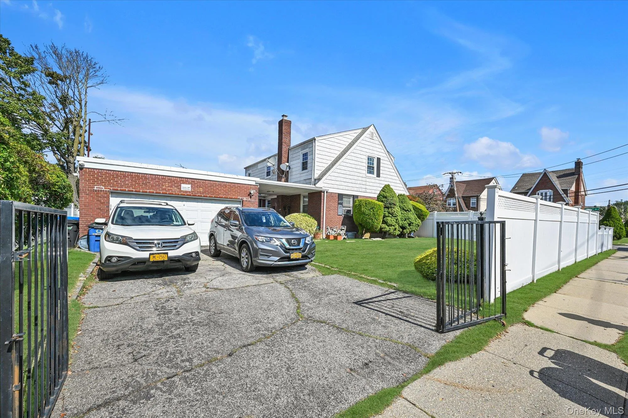 View of front facade featuring a fenced front yard, brick siding, asphalt driveway, and a garage View of front facade featuring a fenced front yard, brick siding, asphalt driveway, and a garage