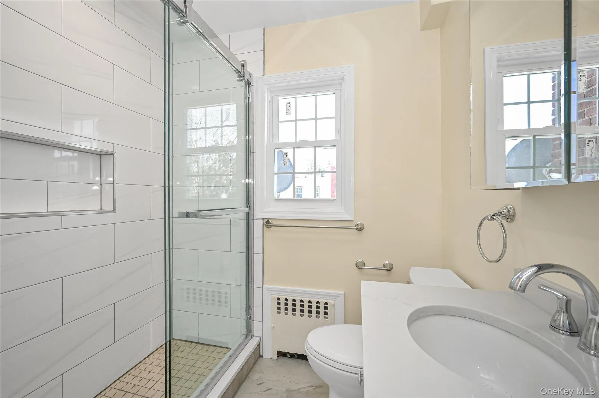 Bathroom featuring a shower stall, vanity, radiator heating unit, and plenty of natural light Bathroom featuring a shower stall, vanity, radiator heating unit, and plenty of natural light