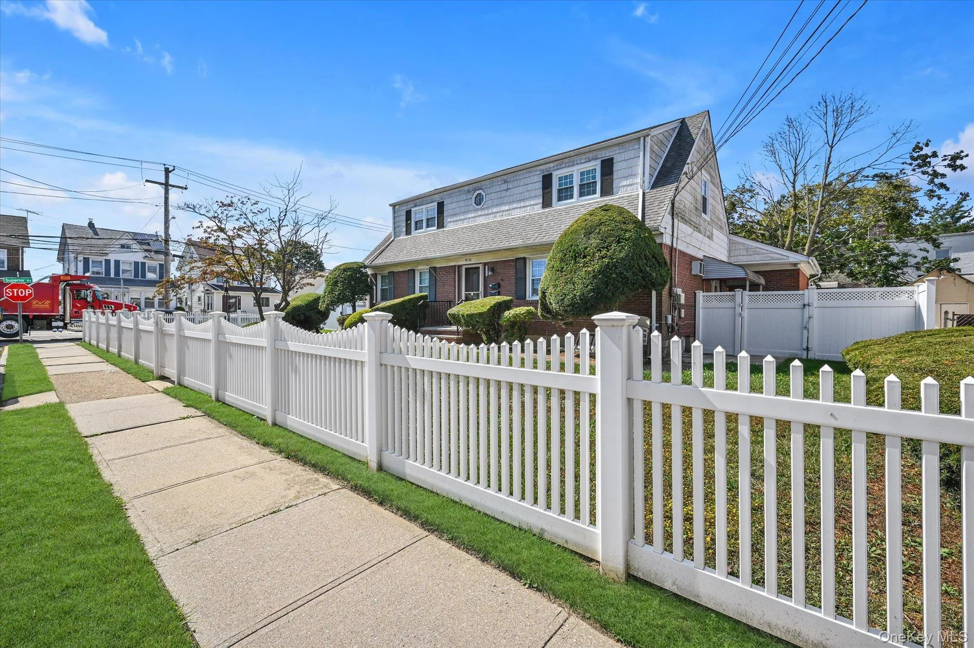 View of front facade with brick siding, a fenced front yard, and a shingled roof View of front facade with brick siding, a fenced front yard, and a shingled roof