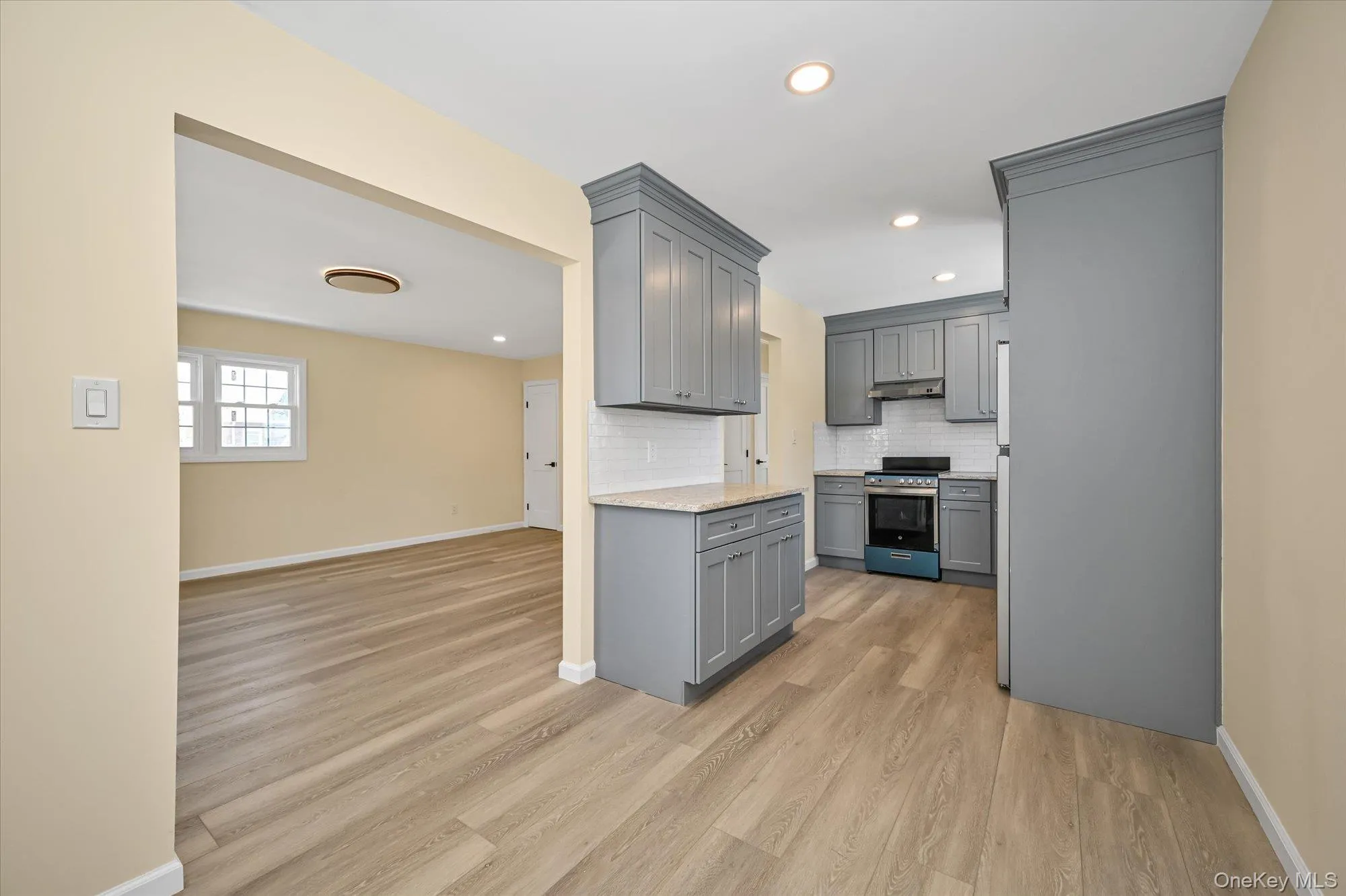 Kitchen featuring gray cabinets, stainless steel electric stove, tasteful backsplash, light wood-style flooring, and recessed lighting Kitchen featuring gray cabinets, stainless steel electric stove, tasteful backsplash, light wood-style flooring, and recessed lighting