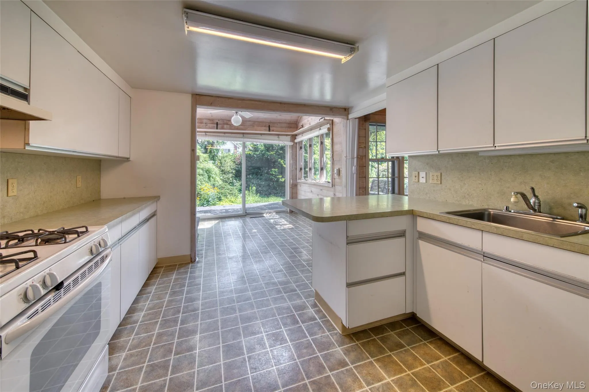 Kitchen featuring tasteful backsplash, a peninsula, gas range gas stove, and light countertops Kitchen featuring tasteful backsplash, a peninsula, gas range gas stove, and light countertops