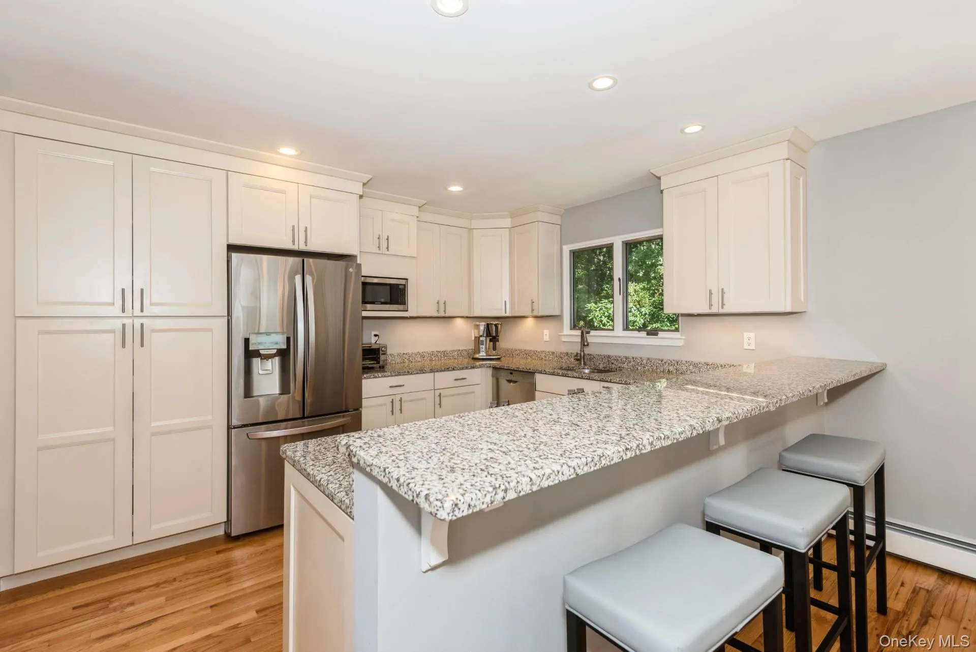 Kitchen with stainless steel appliances, a kitchen bar, a peninsula, white cabinets, and recessed lighting Kitchen with stainless steel appliances, a kitchen bar, a peninsula, white cabinets, and recessed lighting
