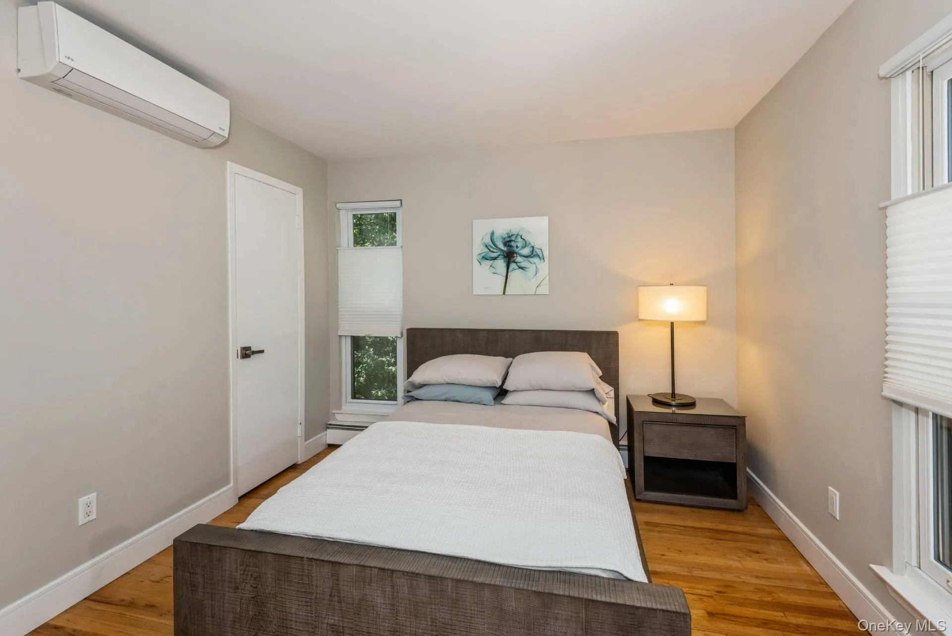 Bedroom featuring a wall mounted AC and light wood-style floors Bedroom featuring a wall mounted AC and light wood-style floors