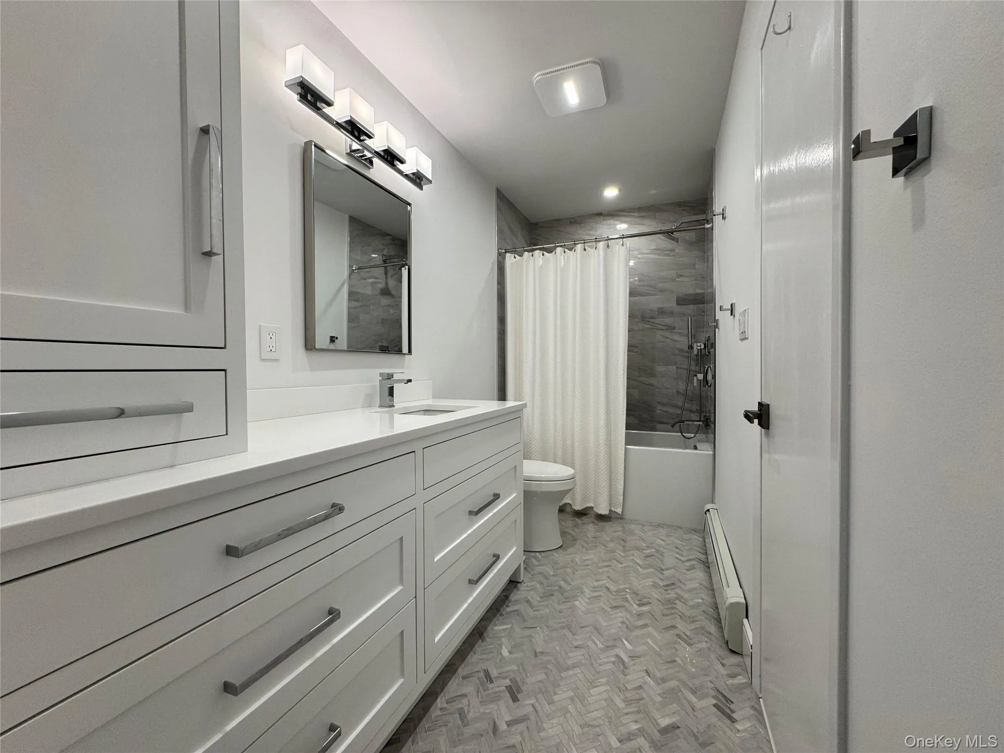 Bathroom with shower / bath combination with curtain, vanity, and baseboard heating Bathroom with shower / bath combination with curtain, vanity, and baseboard heating