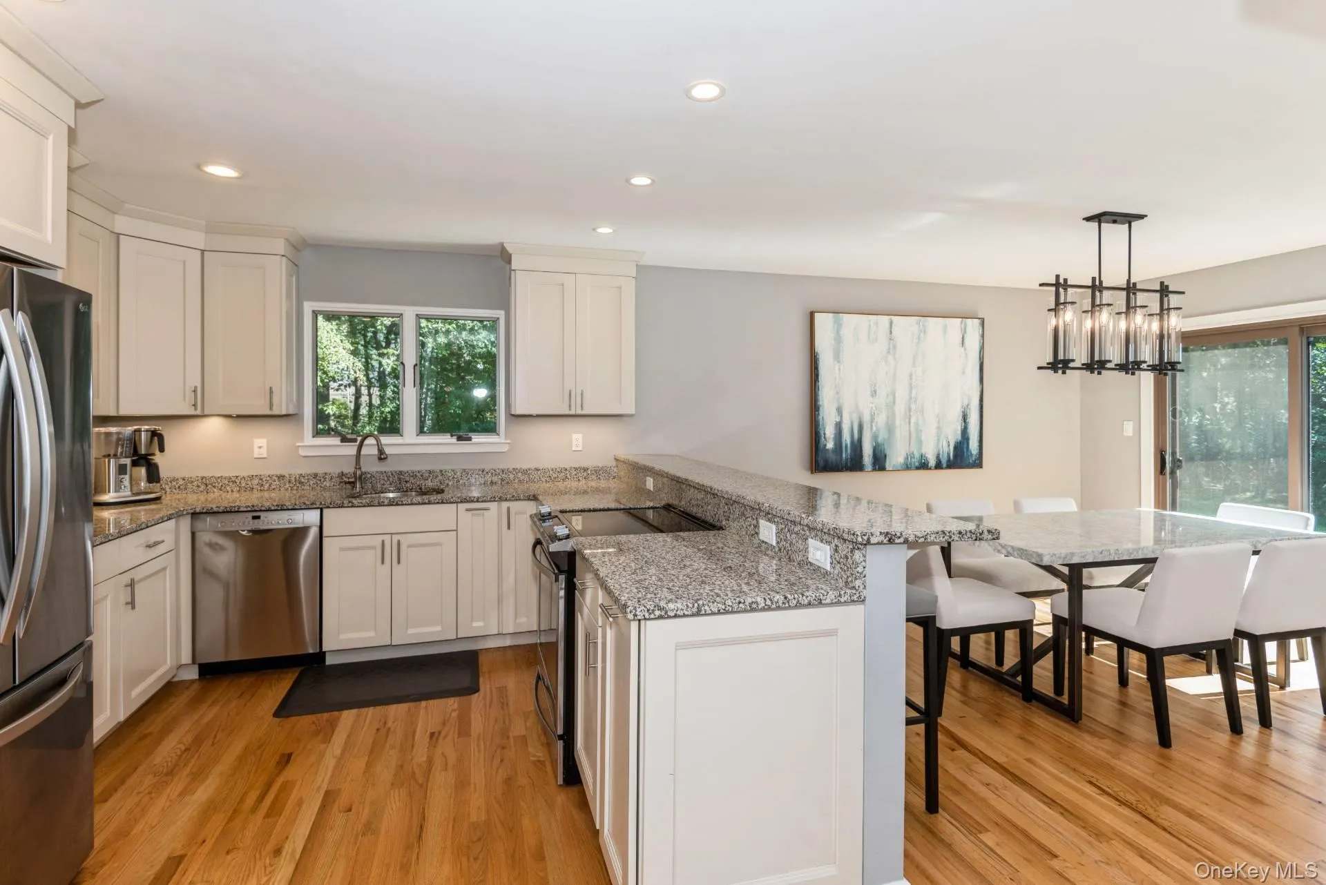 Kitchen featuring stainless steel appliances, light stone countertops, light wood finished floors, recessed lighting, and a kitchen breakfast bar Kitchen featuring stainless steel appliances, light stone countertops, light wood finished floors, recessed lighting, and a kitchen breakfast bar