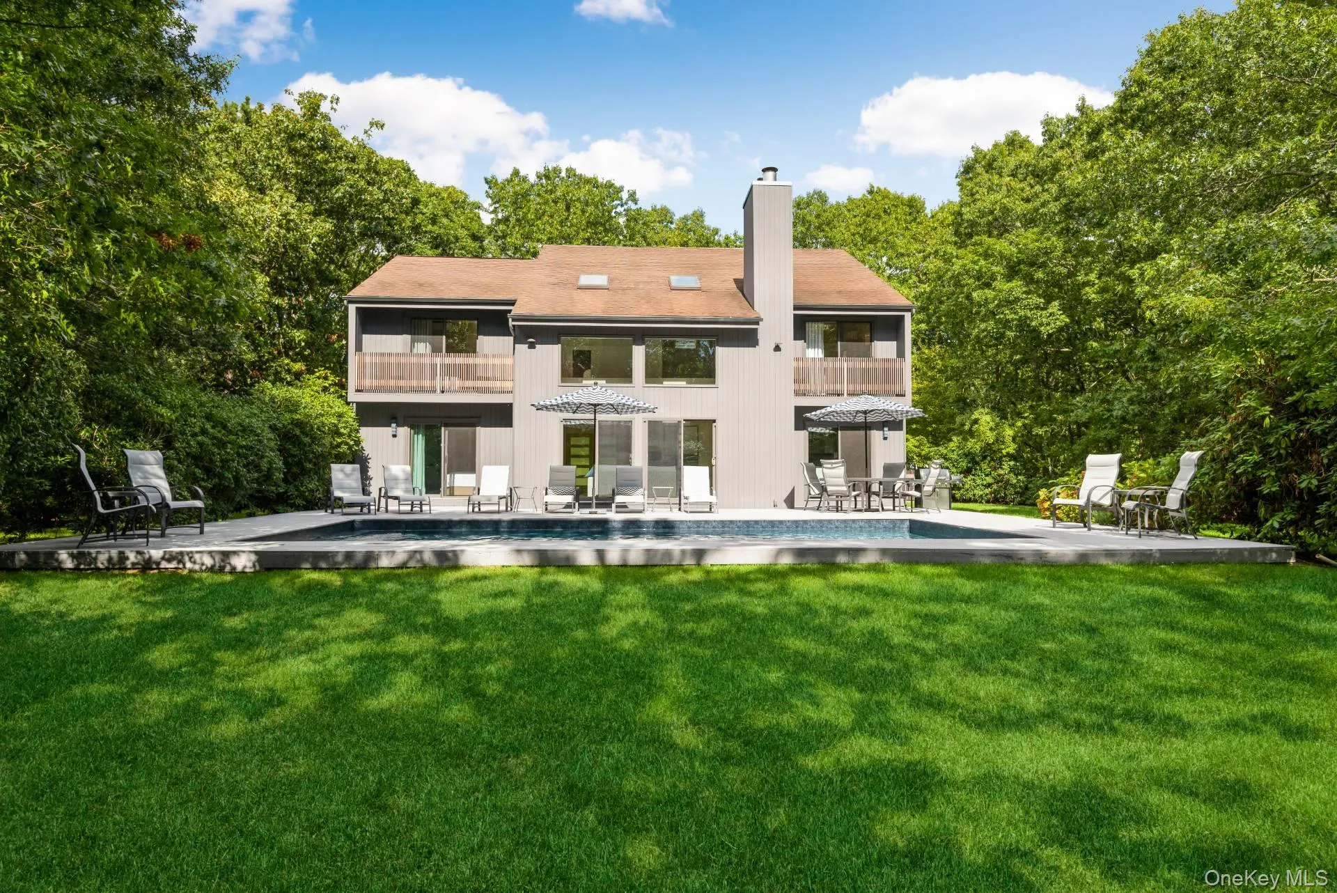 Rear view of property featuring a patio area, a balcony, a lawn, and a chimney Rear view of property featuring a patio area, a balcony, a lawn, and a chimney