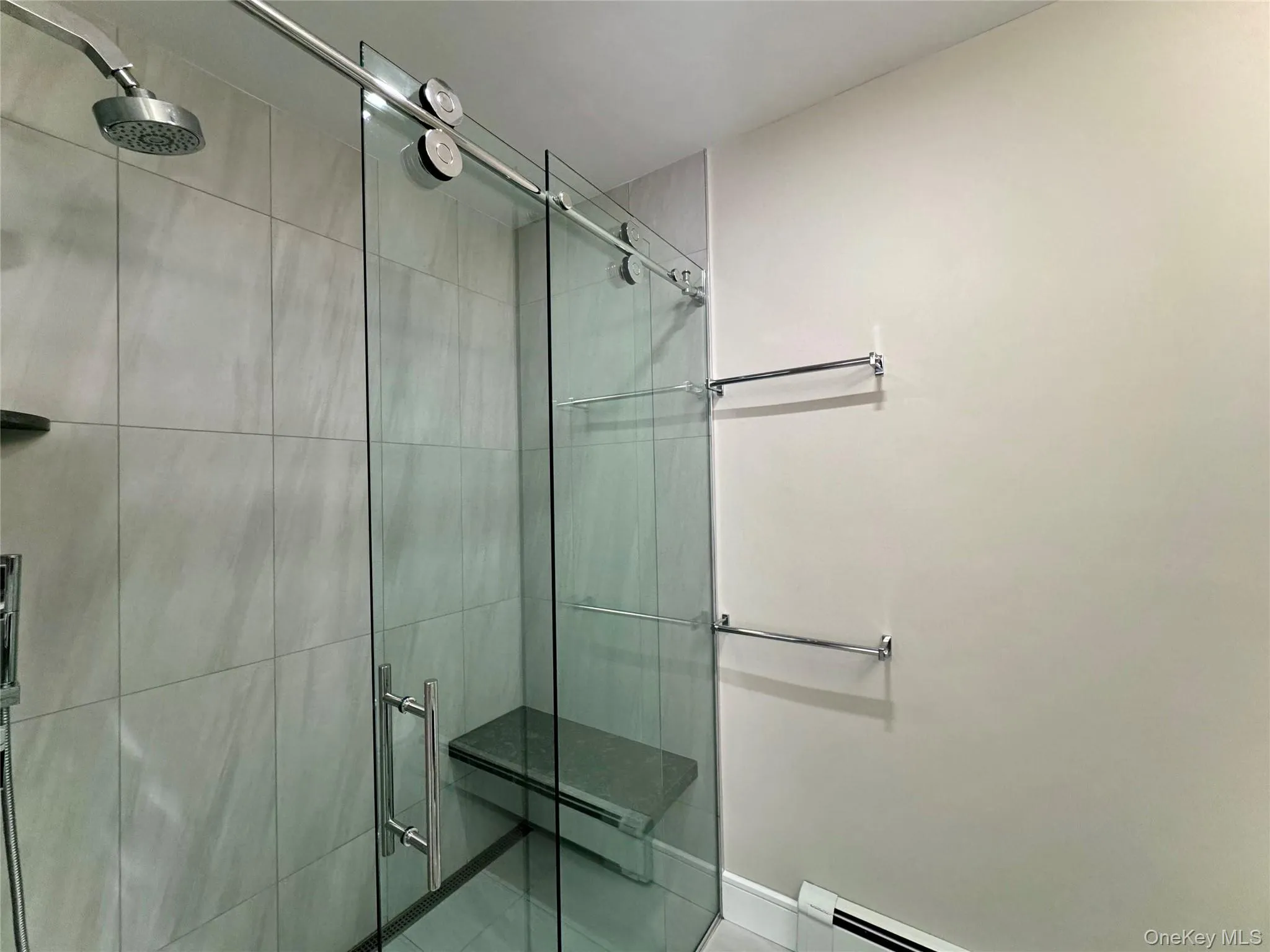 Full bathroom featuring a stall shower, a baseboard radiator, and tile patterned floors Full bathroom featuring a stall shower, a baseboard radiator, and tile patterned floors