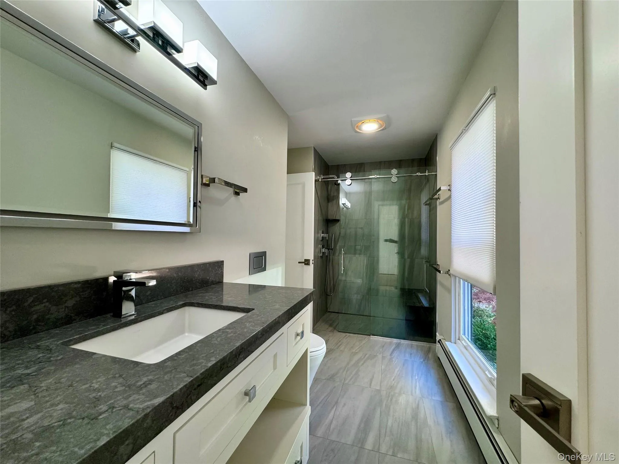 Full bath featuring a baseboard heating unit, vanity, and a stall shower Full bath featuring a baseboard heating unit, vanity, and a stall shower