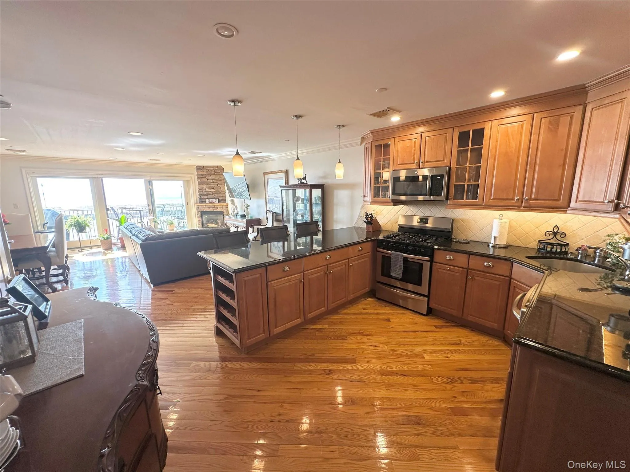 Kitchen with brown cabinets, open floor plan, glass insert cabinets, a peninsula, and crown molding Kitchen with brown cabinets, open floor plan, glass insert cabinets, a peninsula, and crown molding