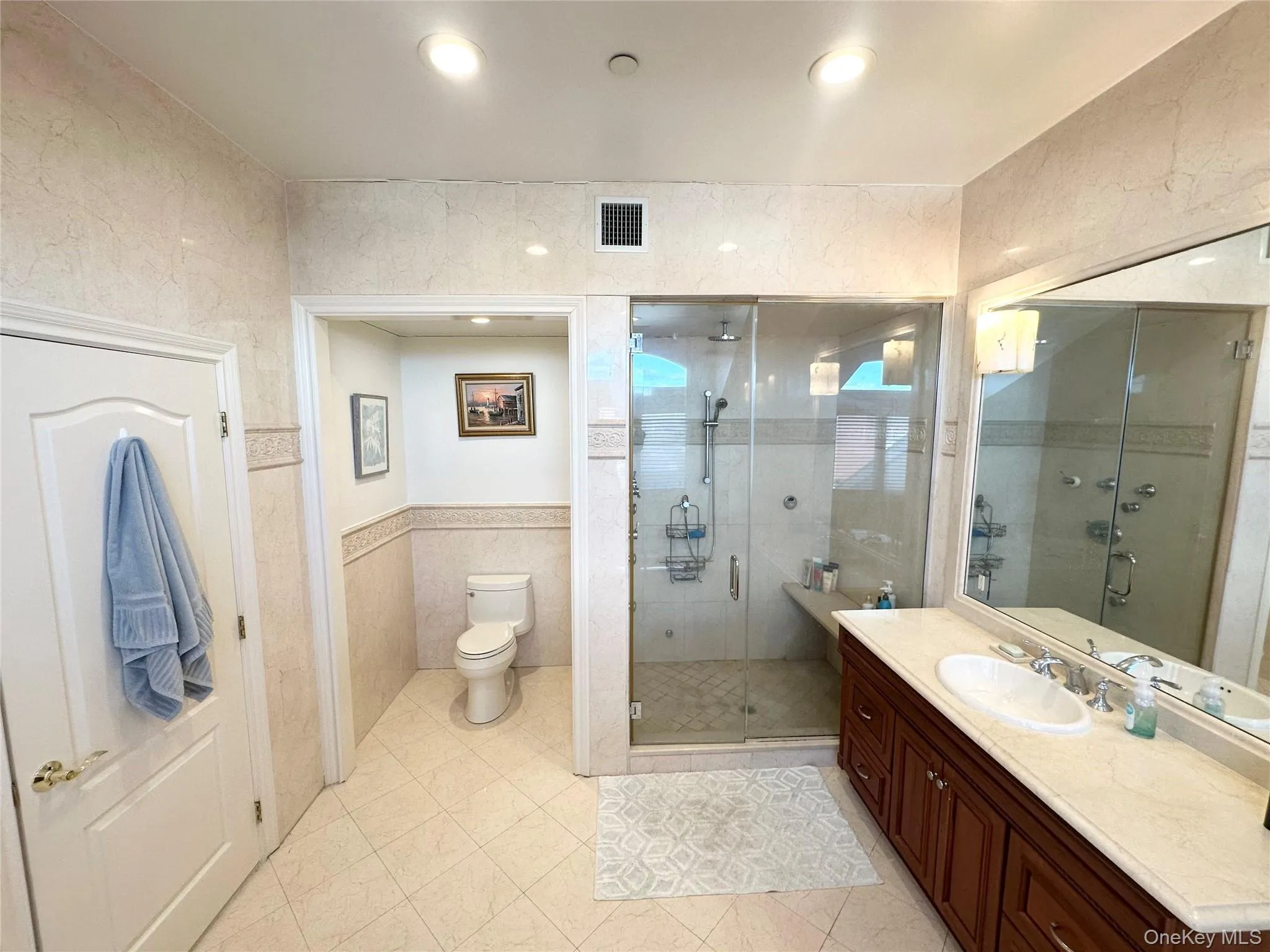 Bathroom with vanity, a shower stall, tile walls, light tile patterned floors, and recessed lighting Bathroom with vanity, a shower stall, tile walls, light tile patterned floors, and recessed lighting