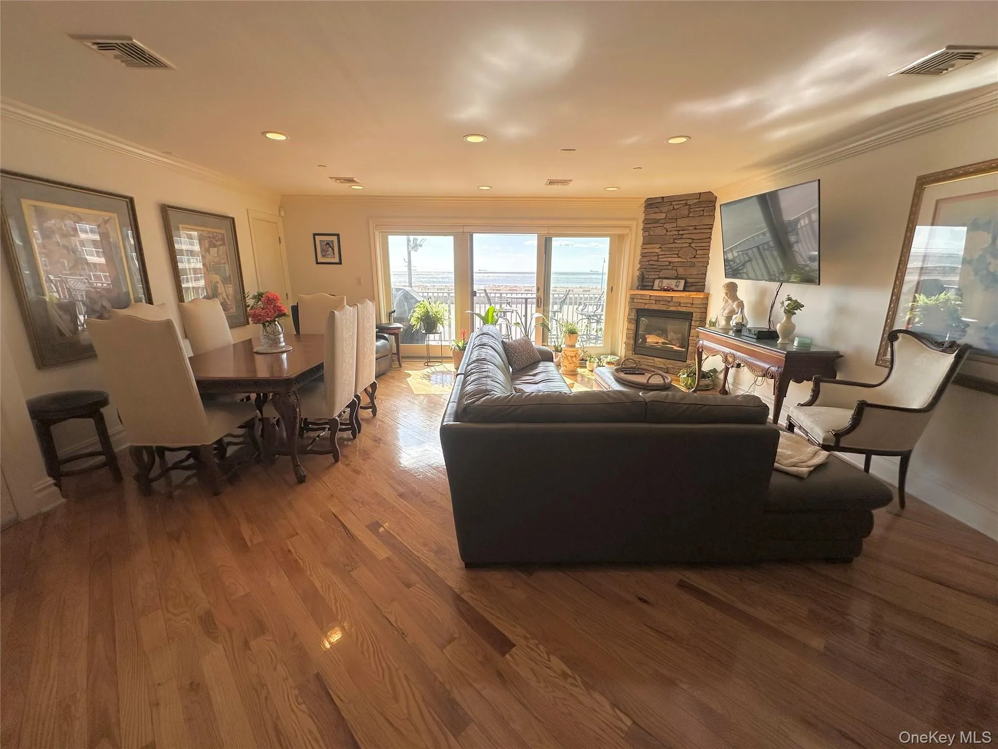 Living room featuring crown molding, wood finished floors, a stone fireplace, and recessed lighting Living room featuring crown molding, wood finished floors, a stone fireplace, and recessed lighting