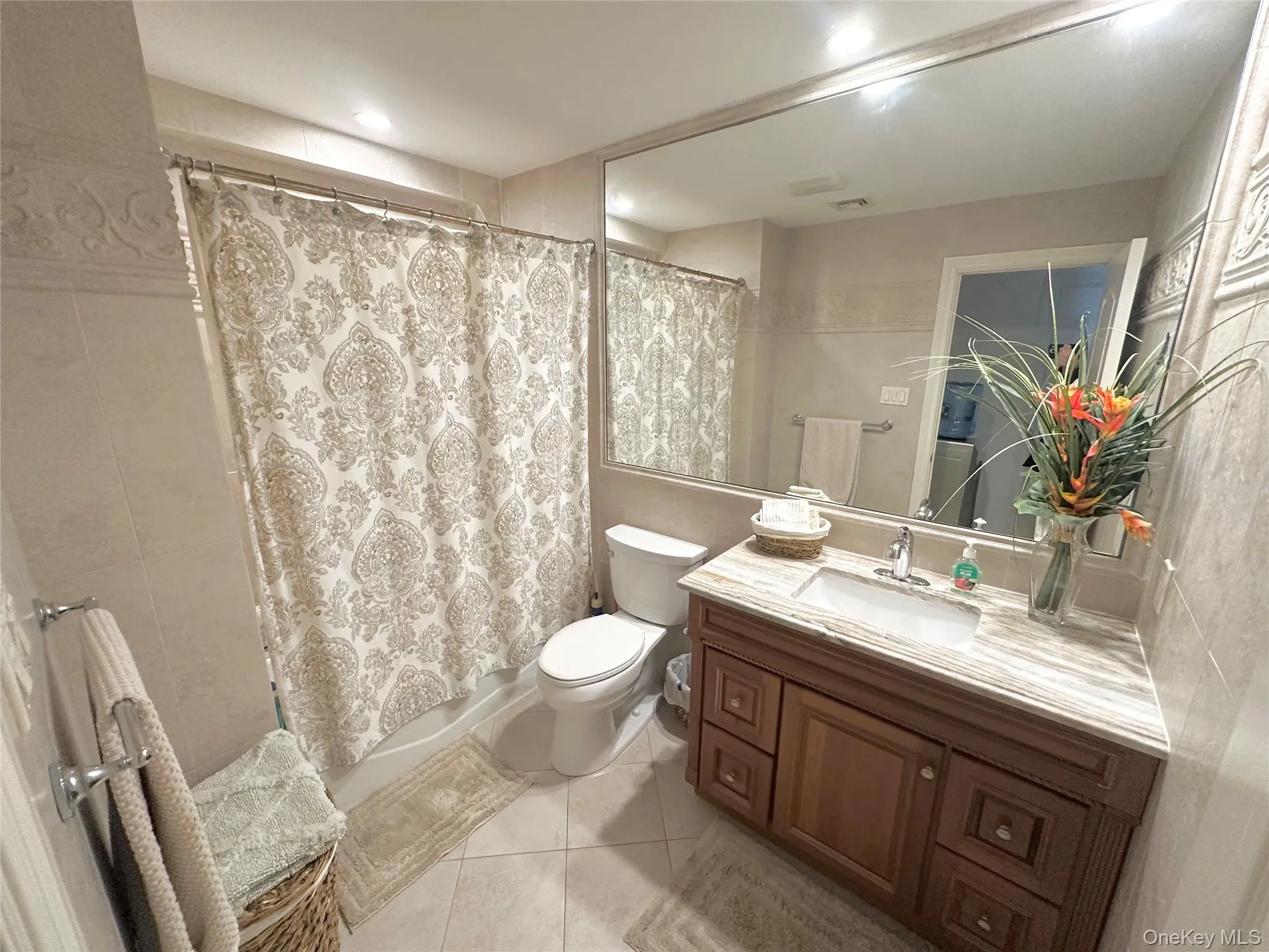 Bathroom with vanity, light tile patterned flooring, shower / tub combo, and tile walls Bathroom with vanity, light tile patterned flooring, shower / tub combo, and tile walls