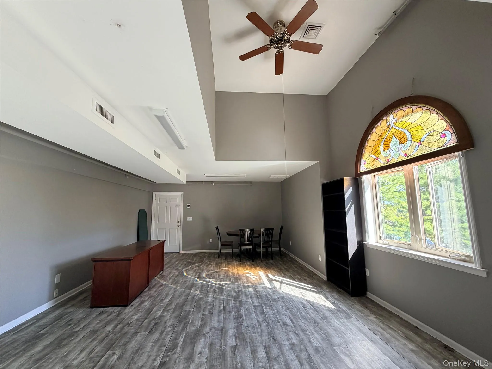 Office space with high vaulted ceiling, wood finished floors, and a ceiling fan Office space with high vaulted ceiling, wood finished floors, and a ceiling fan