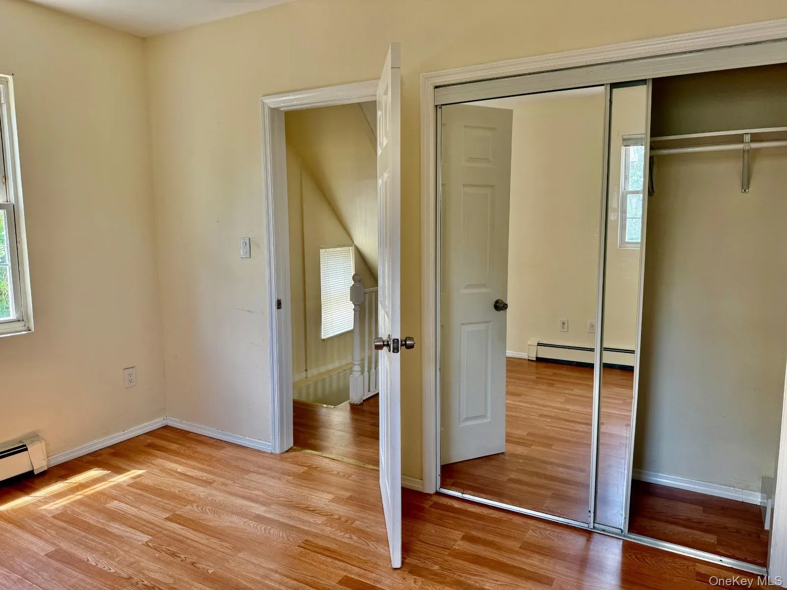 Unfurnished bedroom with a closet, light wood-style floors, and baseboard heating Unfurnished bedroom with a closet, light wood-style floors, and baseboard heating
