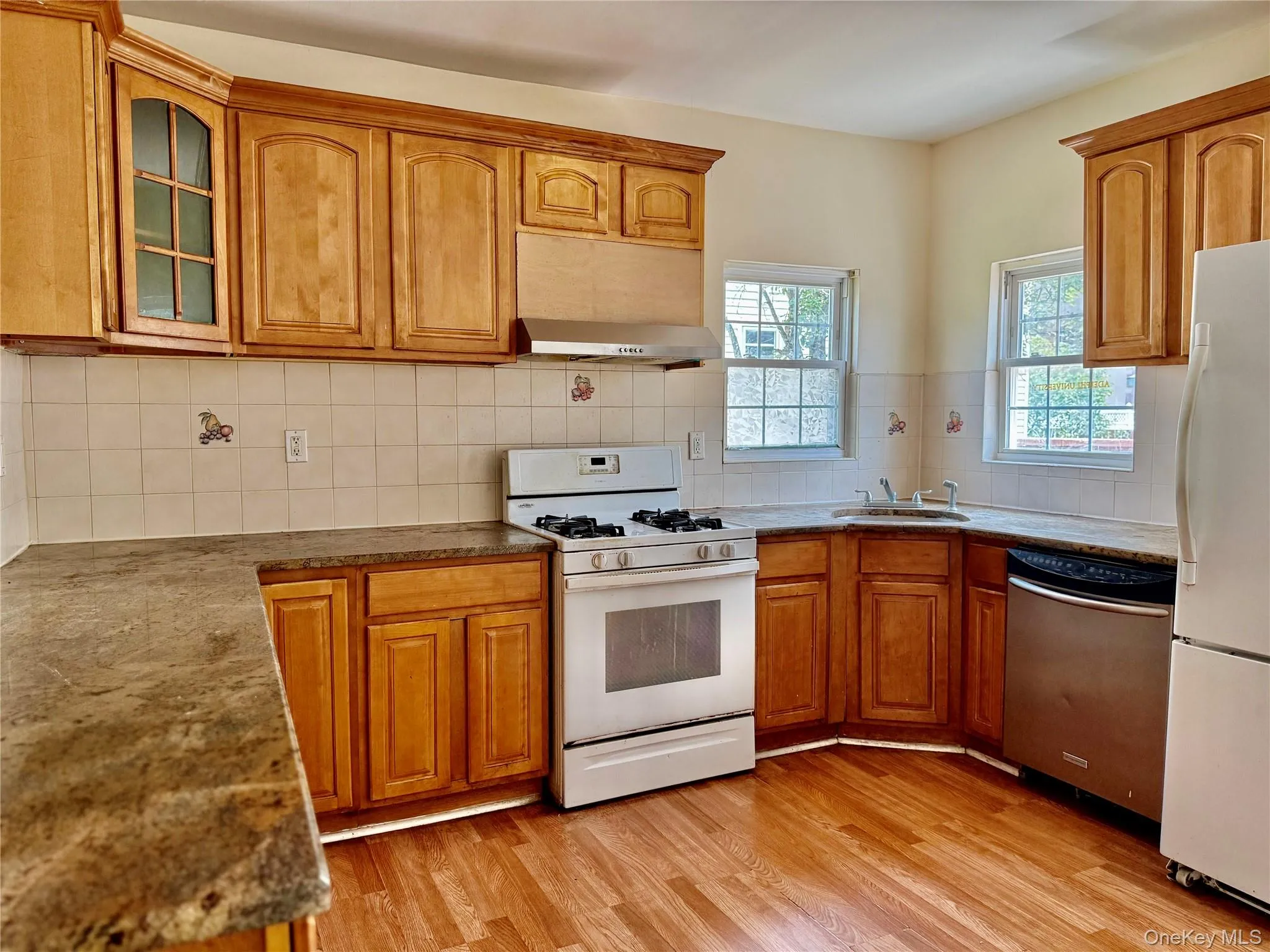 Kitchen with white appliances, brown cabinets, light wood-style floors, and glass insert cabinets Kitchen with white appliances, brown cabinets, light wood-style floors, and glass insert cabinets