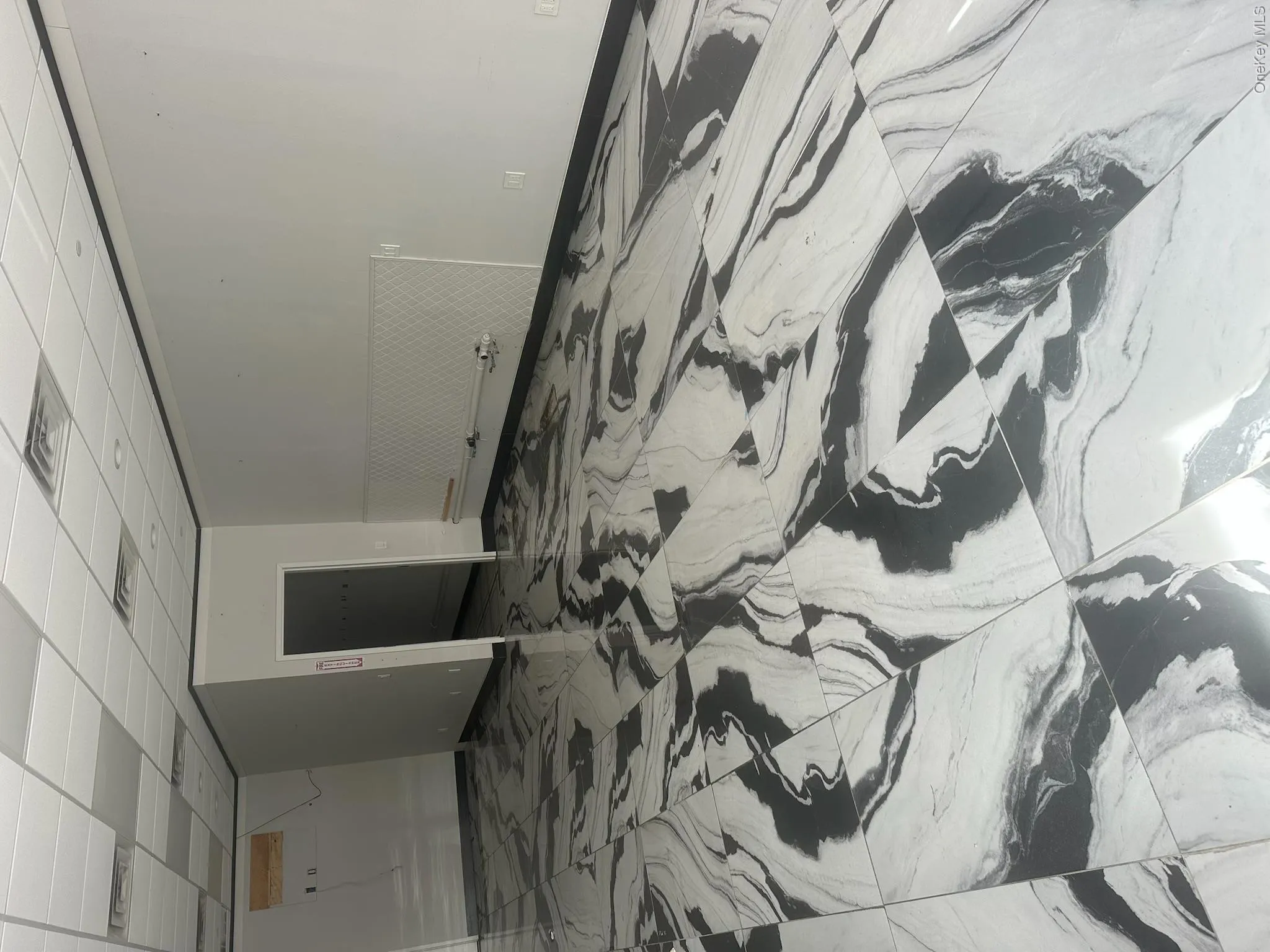 Unfurnished room featuring a drop ceiling and light marble finish flooring Unfurnished room featuring a drop ceiling and light marble finish flooring