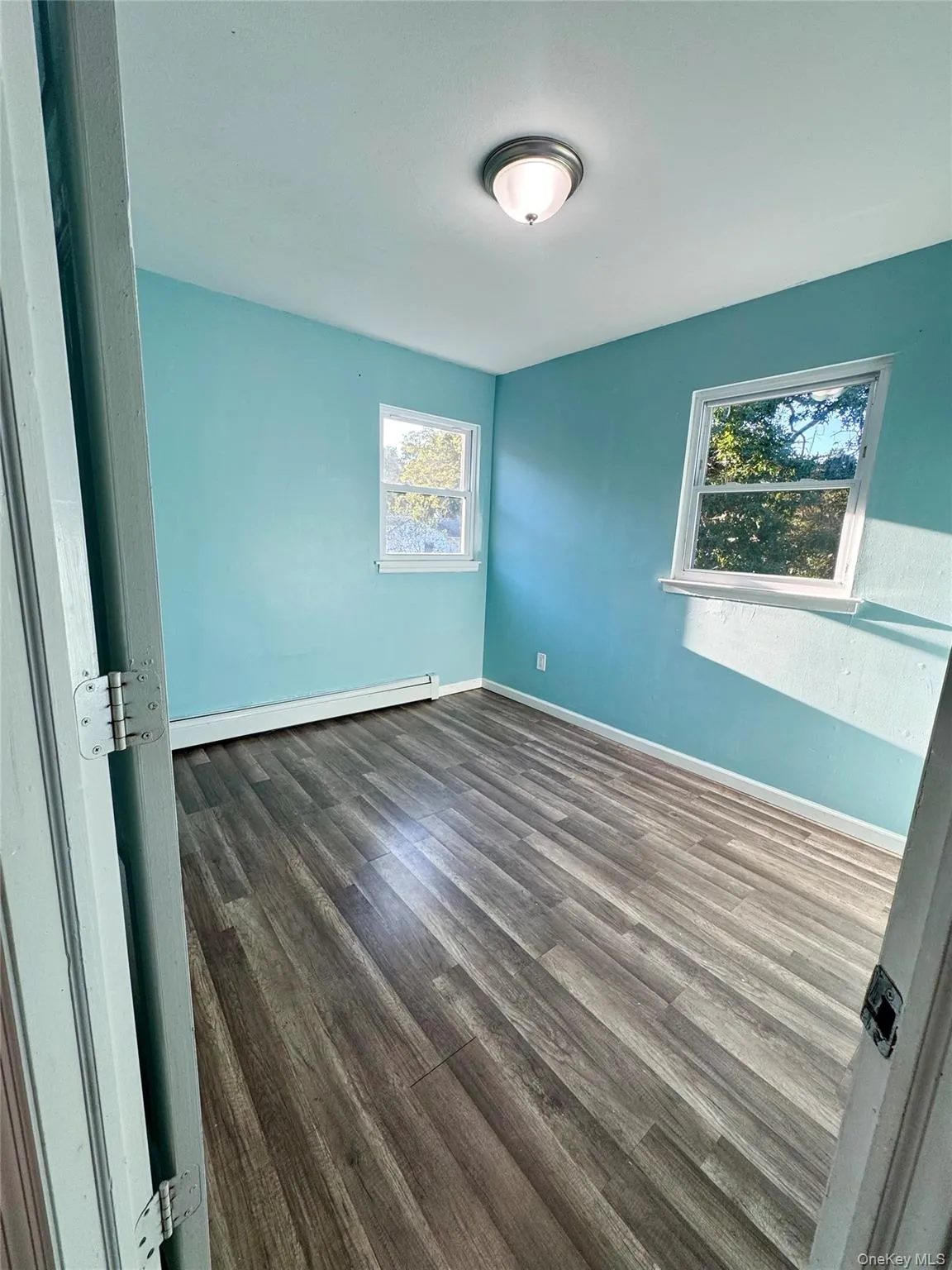 Spare room featuring dark wood-style flooring and a baseboard radiator Spare room featuring dark wood-style flooring and a baseboard radiator