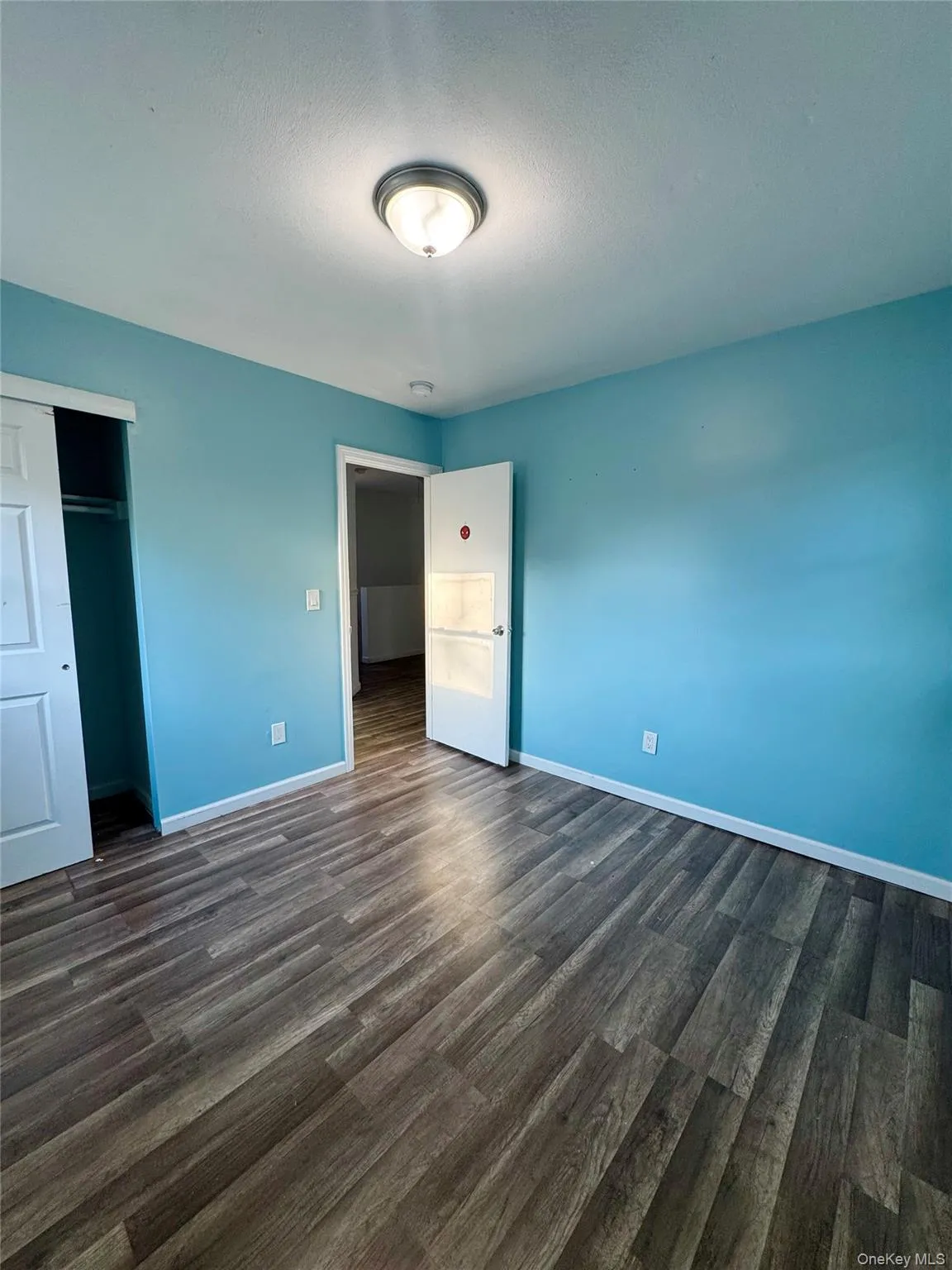 Unfurnished bedroom featuring dark wood finished floors, a closet, and a textured ceiling Unfurnished bedroom featuring dark wood finished floors, a closet, and a textured ceiling