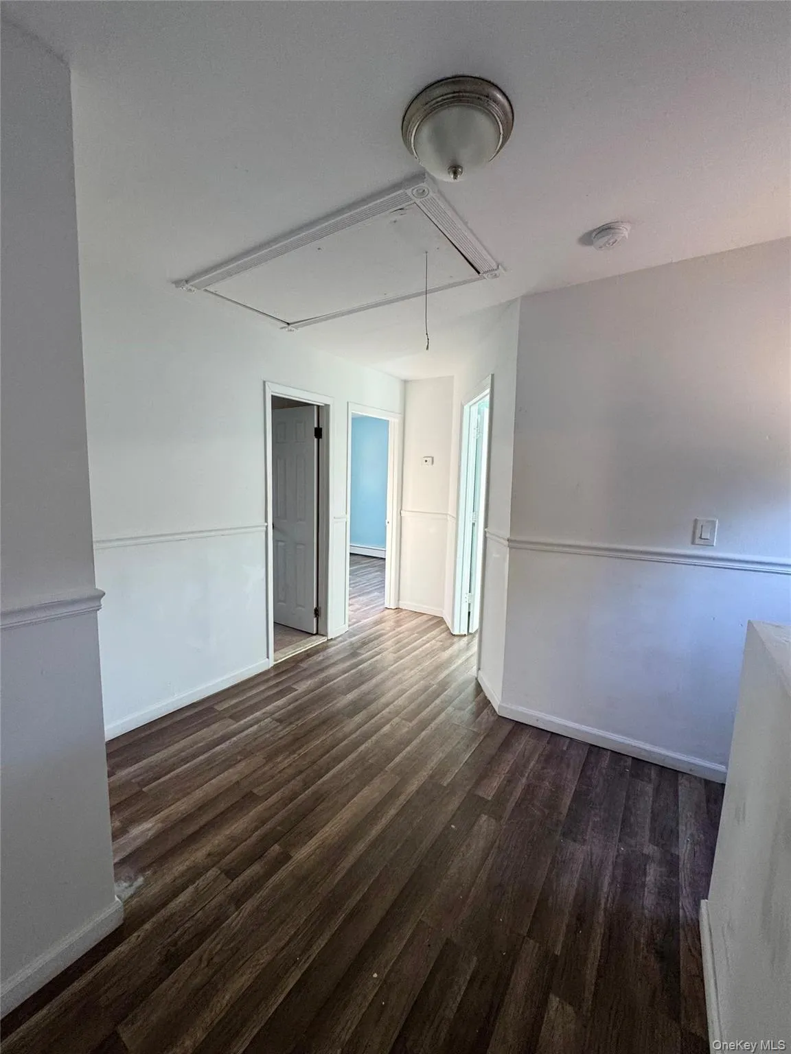 Empty room featuring attic access and dark wood-style flooring Empty room featuring attic access and dark wood-style flooring