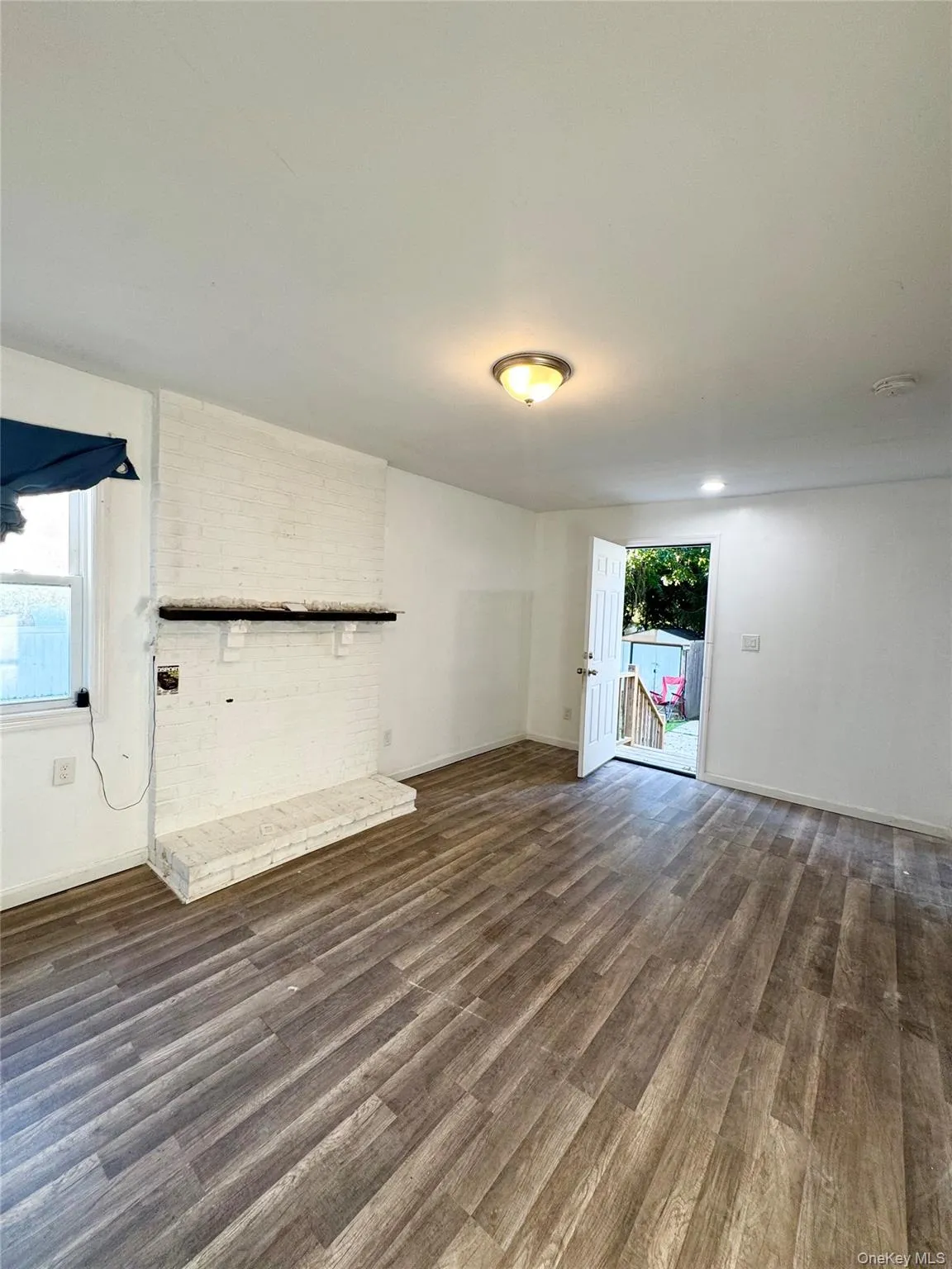 Unfurnished living room featuring dark wood-type flooring and baseboards Unfurnished living room featuring dark wood-type flooring and baseboards