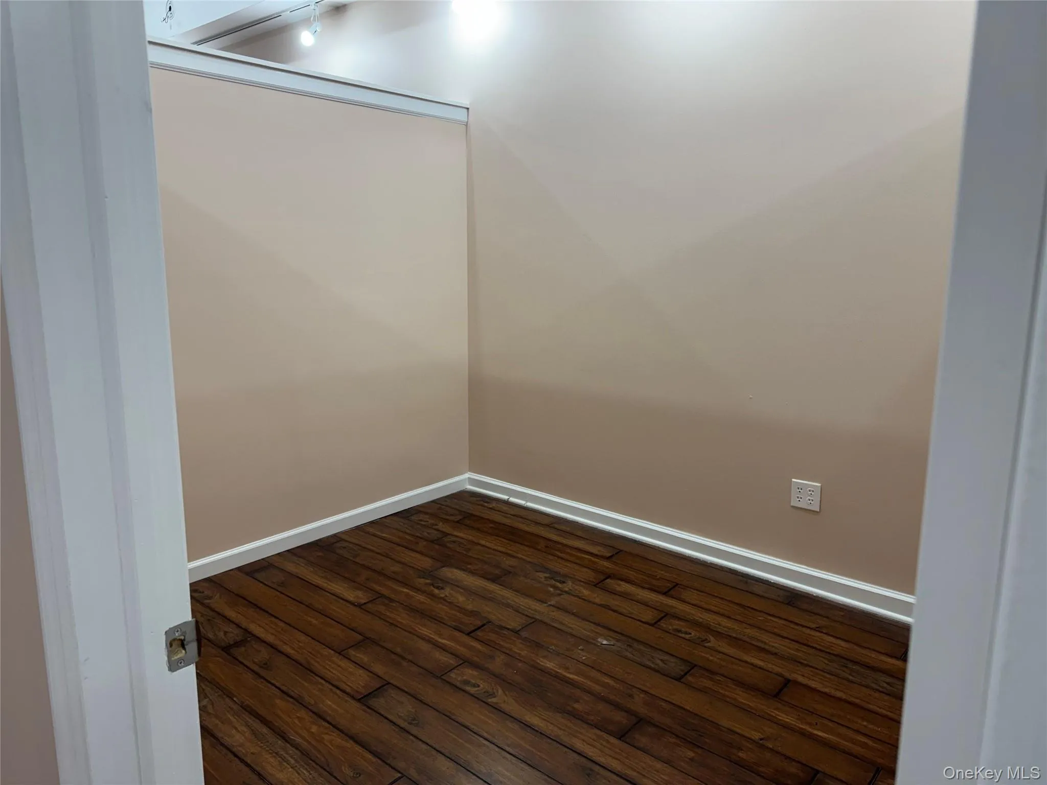 Spare room featuring dark wood-style flooring and baseboards Spare room featuring dark wood-style flooring and baseboards