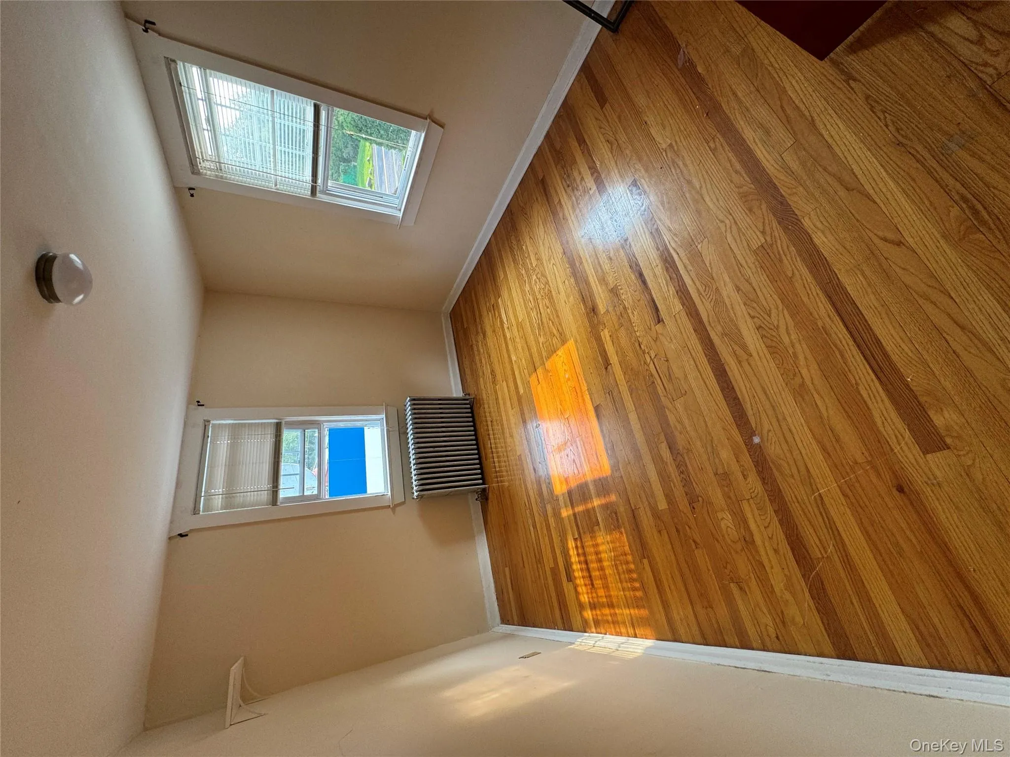 Spare room with plenty of natural light, radiator heating unit, and light wood-type flooring Spare room with plenty of natural light, radiator heating unit, and light wood-type flooring