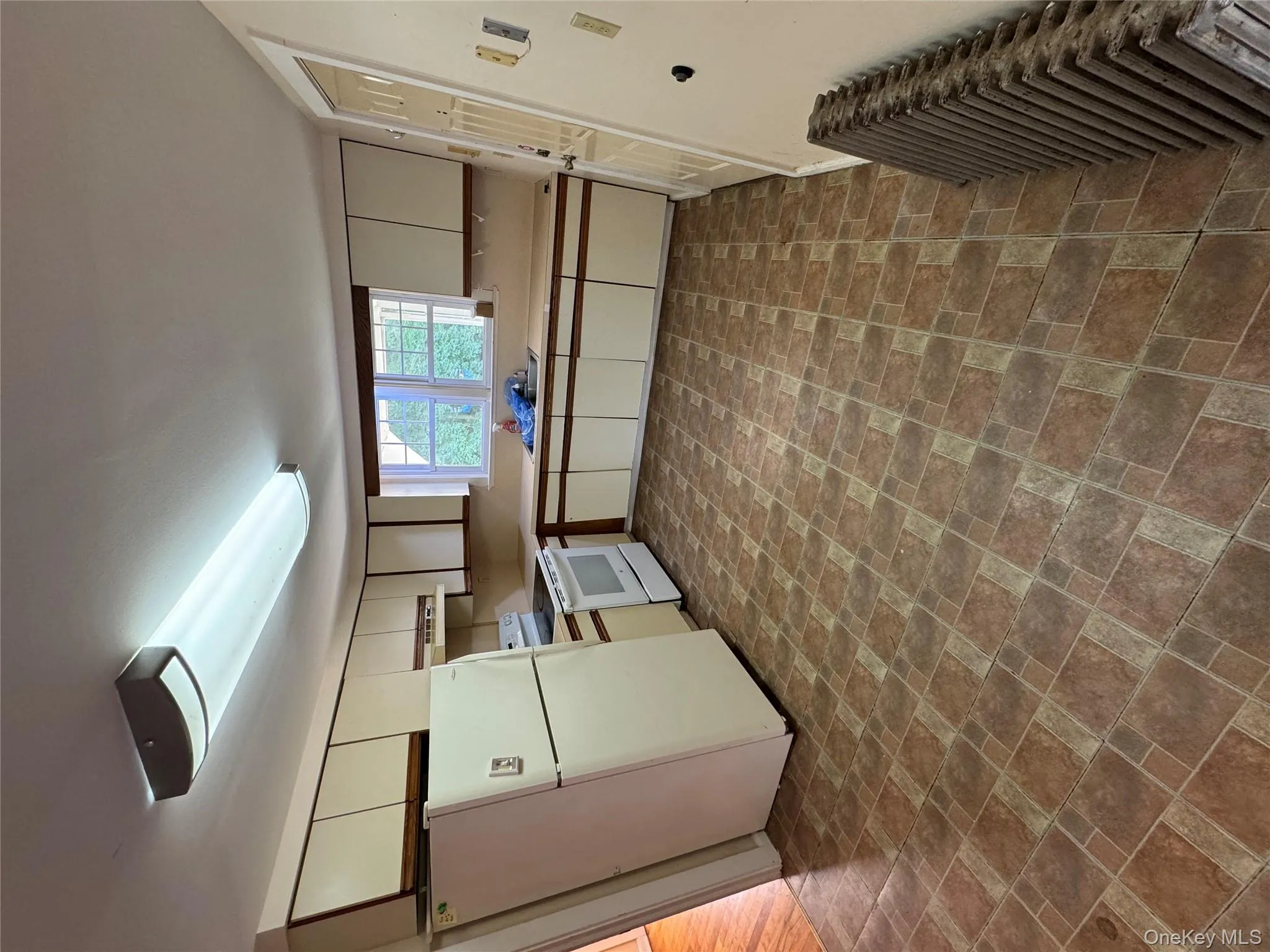 Kitchen with fridge, stove, light countertops, radiator, and brick patterned floors Kitchen with fridge, stove, light countertops, radiator, and brick patterned floors