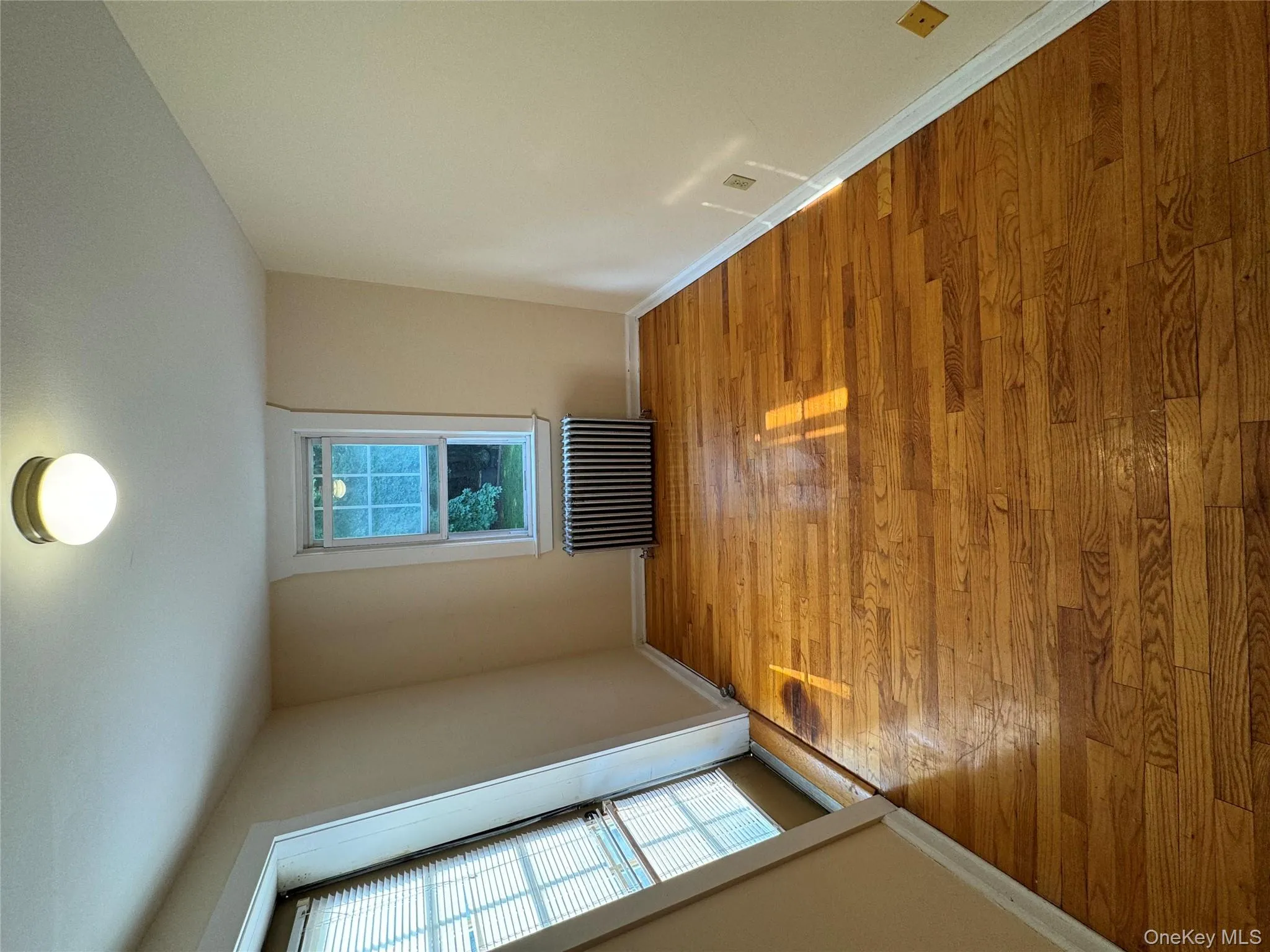 Empty room with radiator heating unit and light wood-style flooring Empty room with radiator heating unit and light wood-style flooring